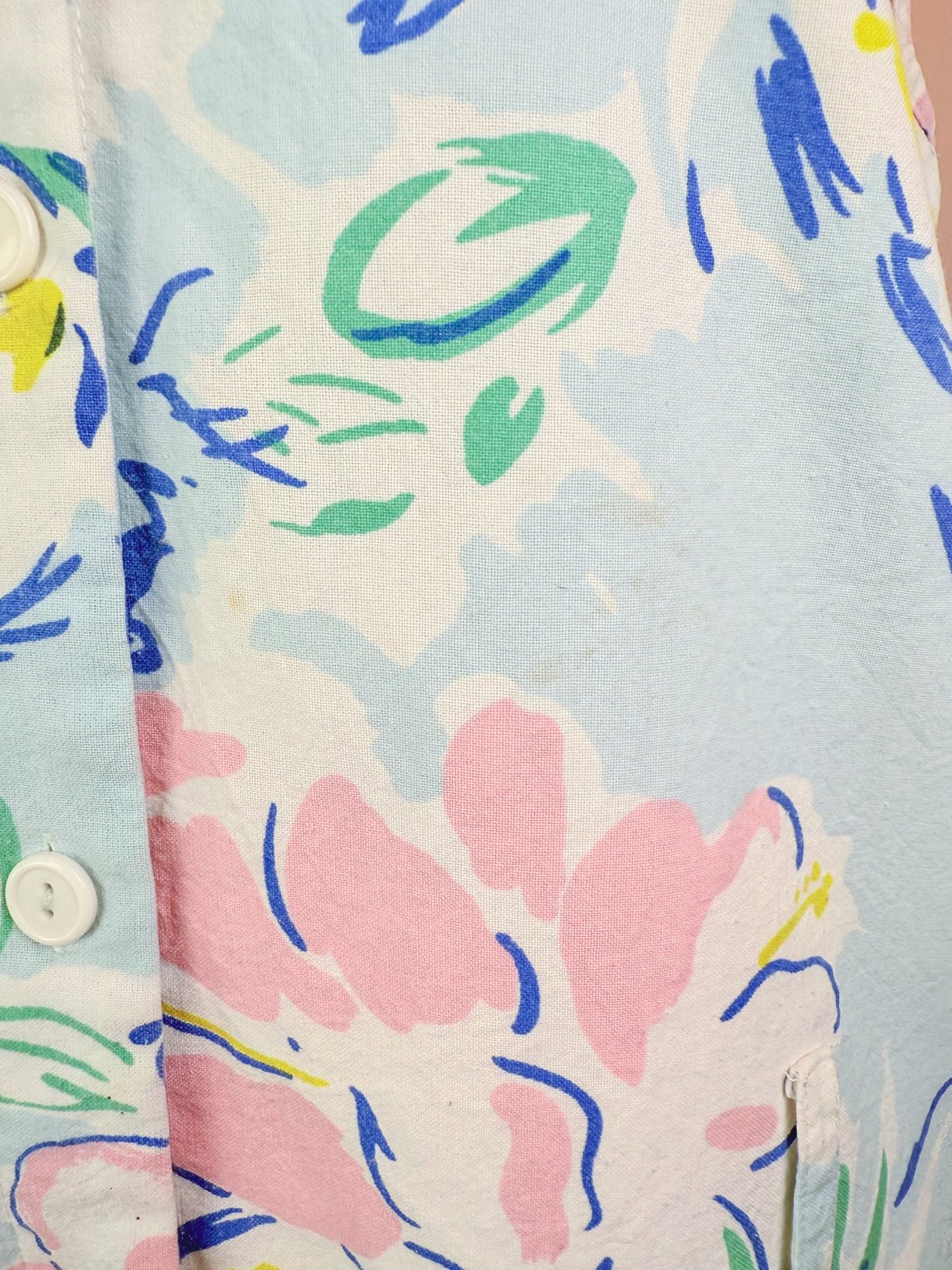 A blue 1980s women's romper featuring a colorful floral print with button details.