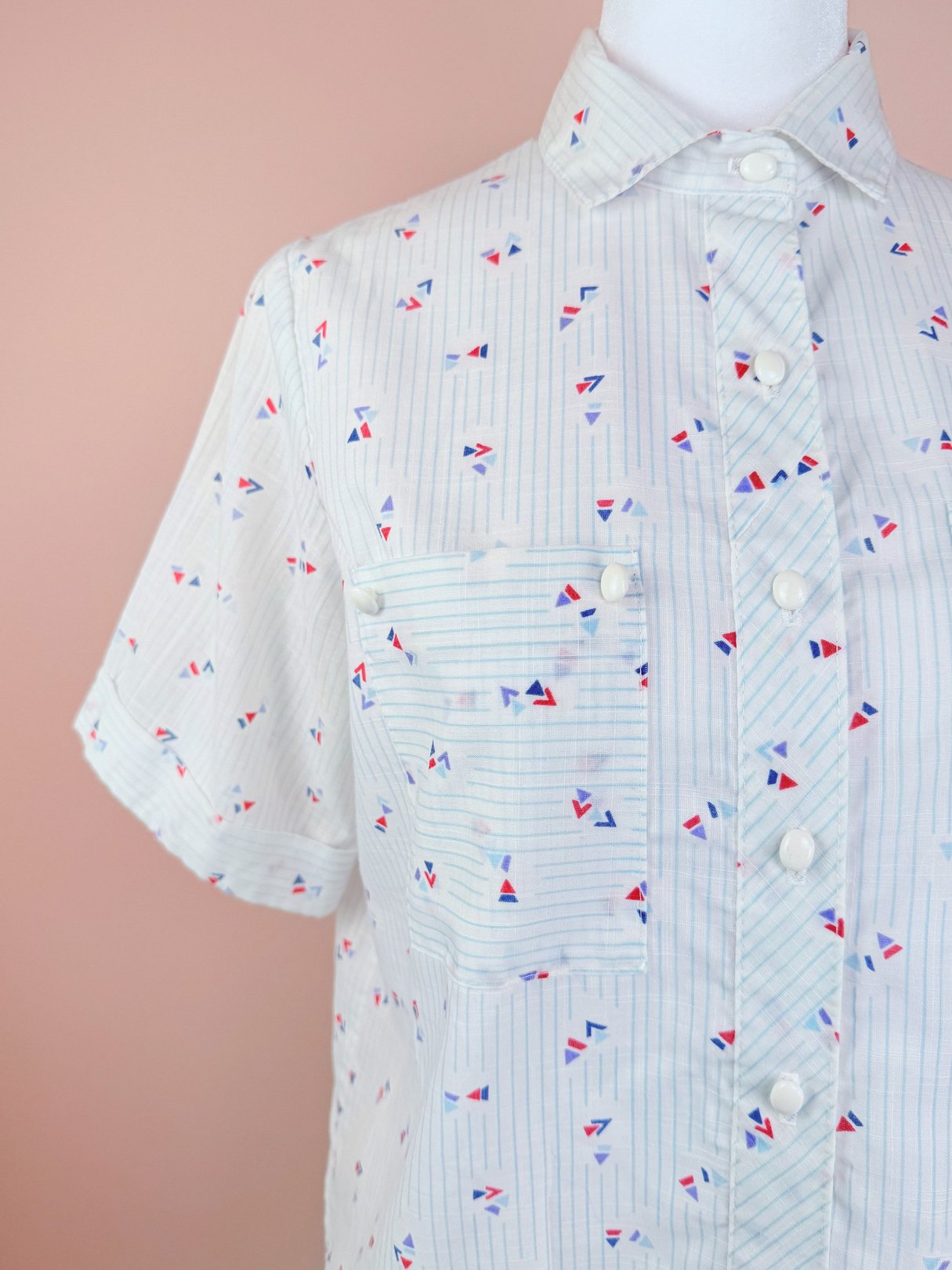 Short-sleeve women's top featuring a blue, white, and red geometric print suitable for the 1980s era.