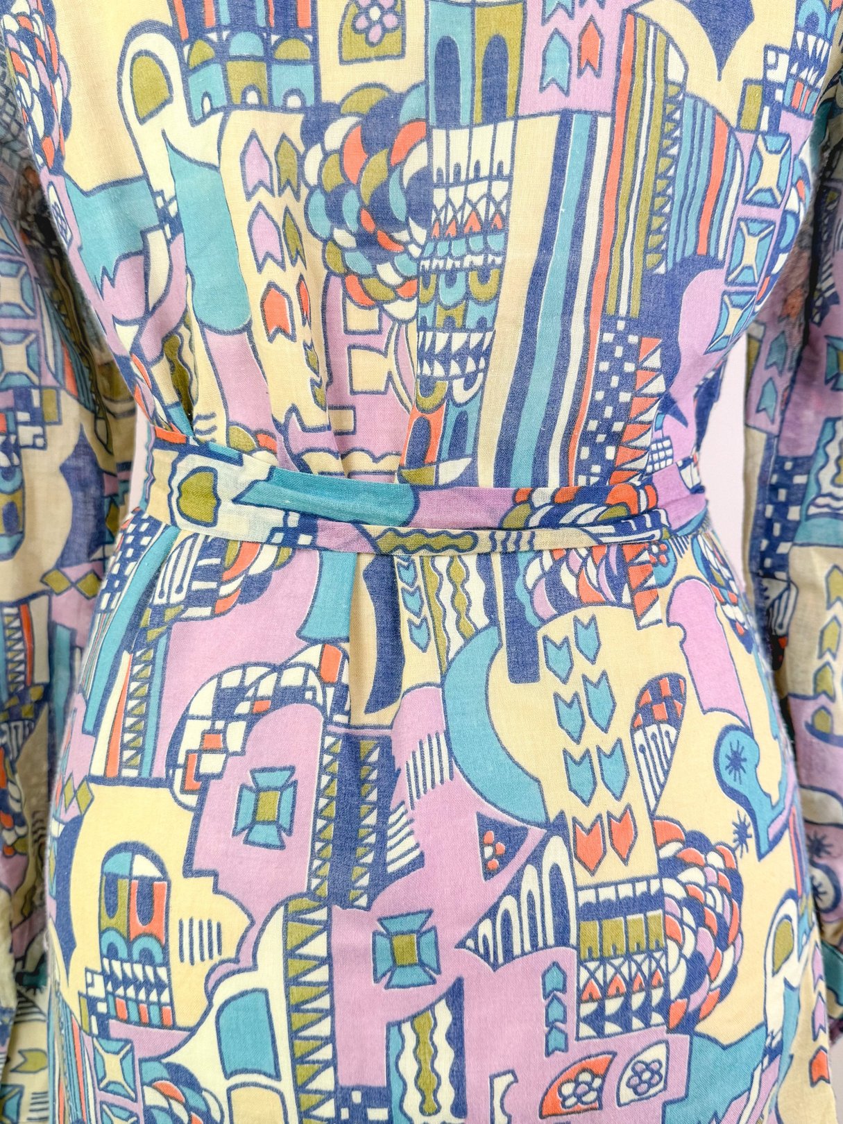 1970's Metropolis Dress in cream with a multicolored abstract pattern and a belted waist.