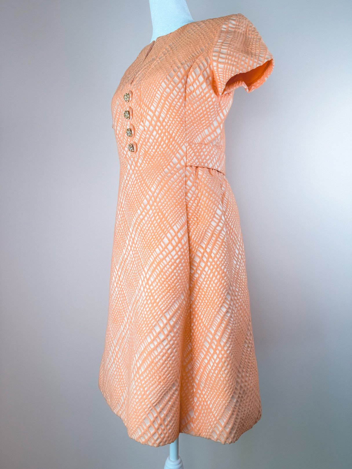 1960s women's orange dress featuring a textured pattern and decorative buttons on the bodice.