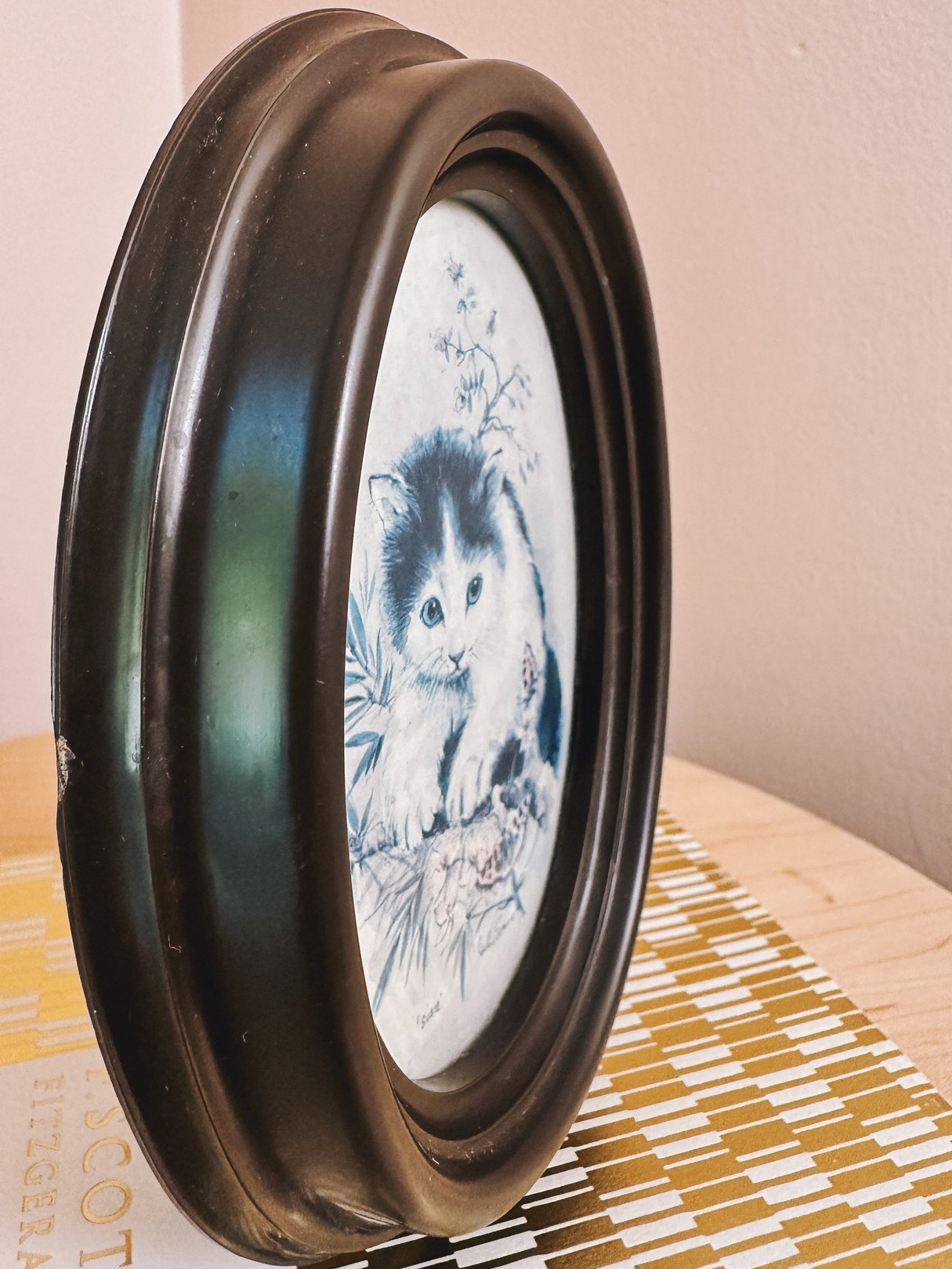 A 1970s blue cat portrait in a round brown frame, meant for home decor.