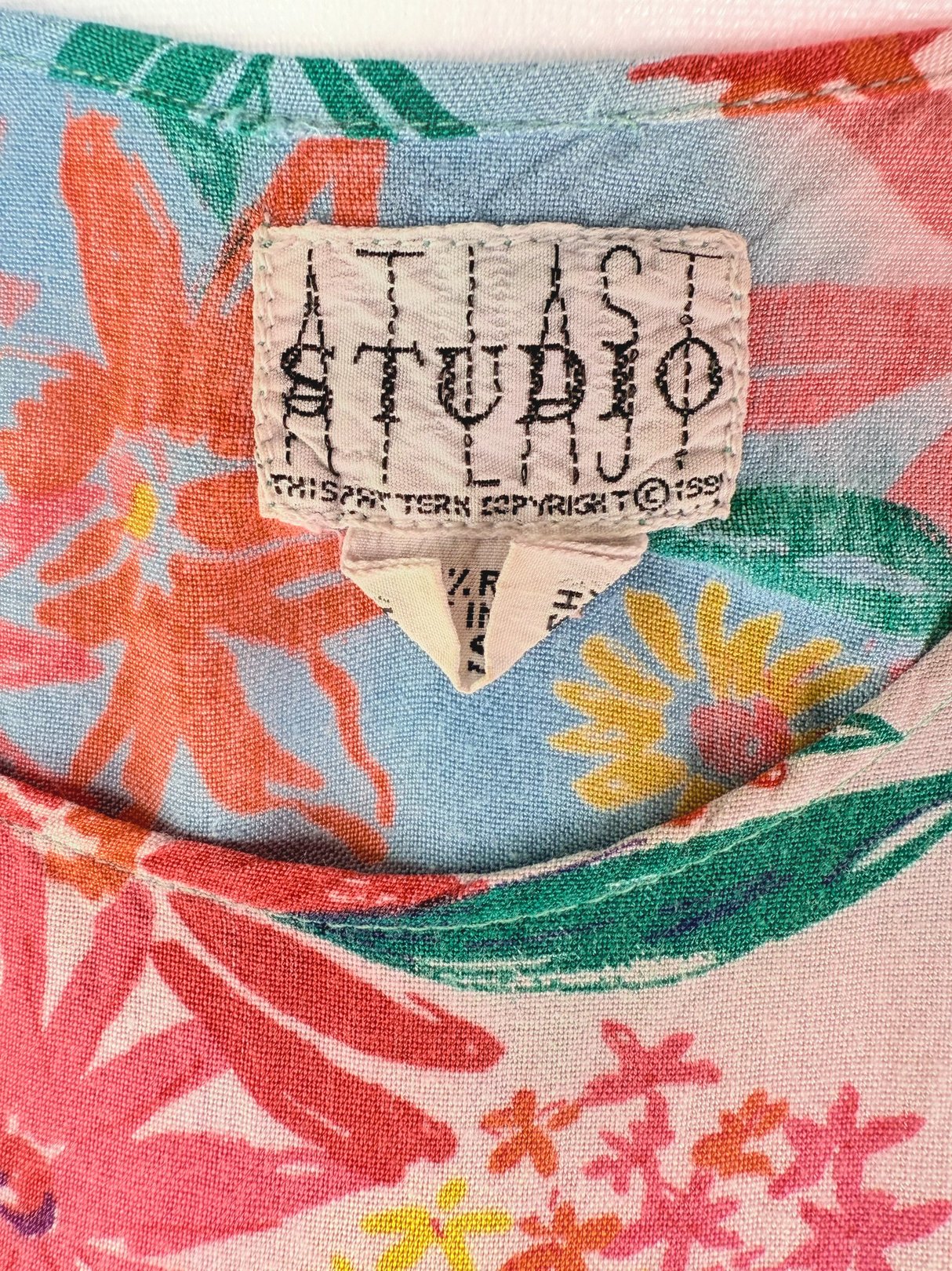 A pink floral dress label from the 1990s featuring vibrant colors and a tropical print.