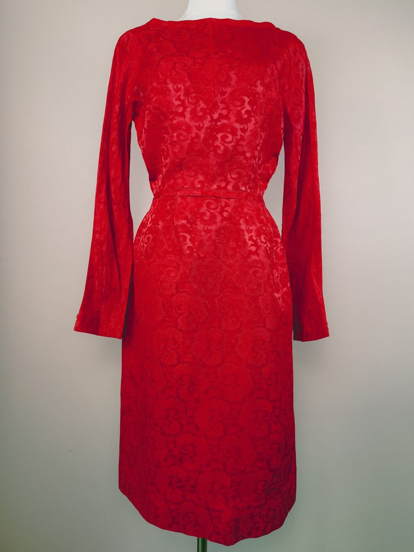 A 1950s women's red damask dress featuring long sleeves and a fitted silhouette.