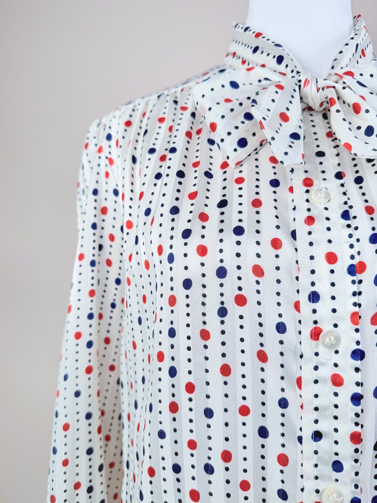 Women's 1980s red, white, and polka dot blouse featuring a bow tie collar and button-up front.