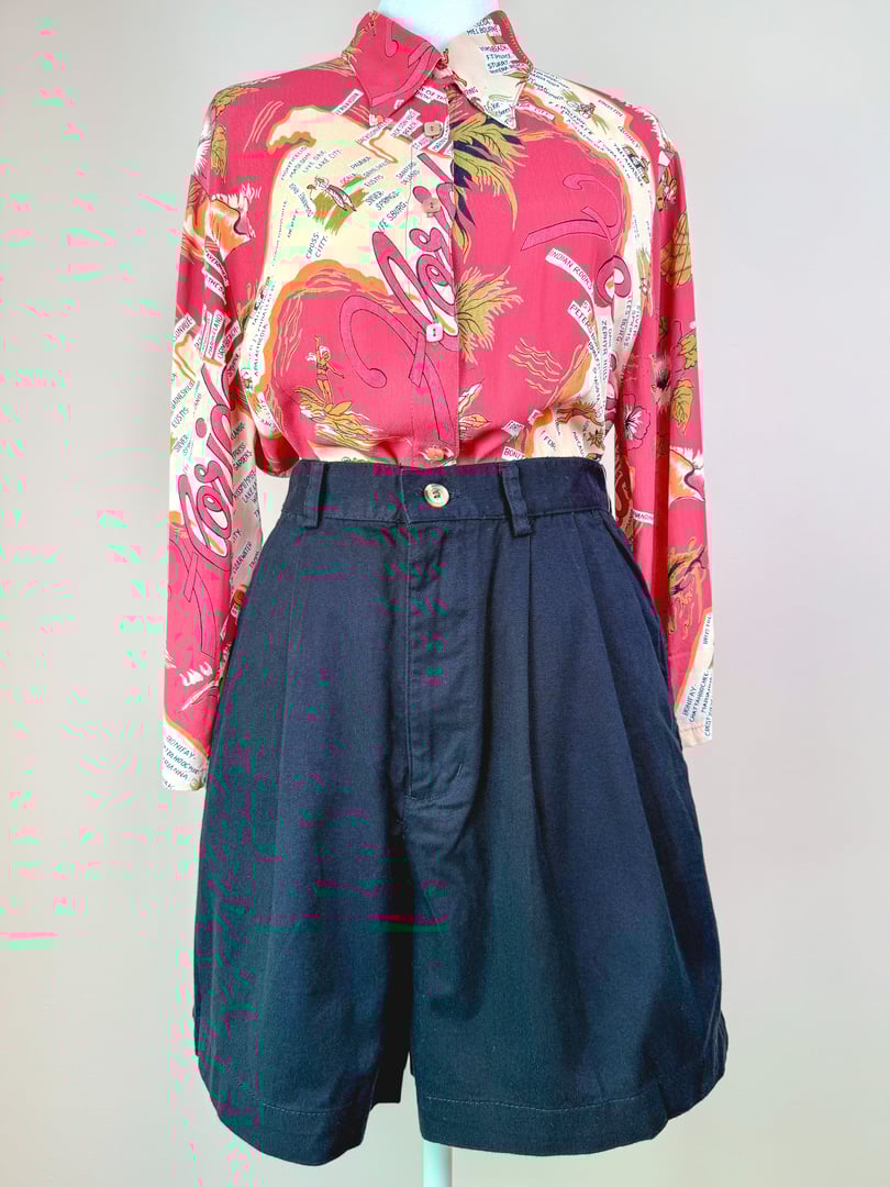 Women’s 1980s black shorts with a high waist and button detail, styled with a vibrant patterned shirt.