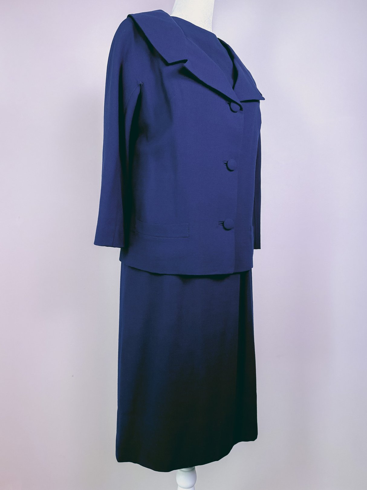 Navy blue 1960s women's dress set featuring a collared jacket with three buttons and a matching skirt.
