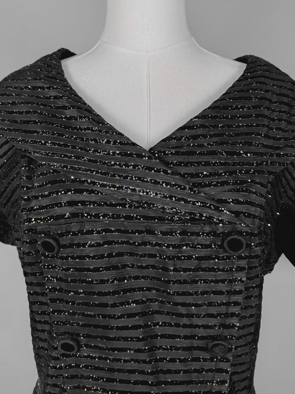 Black 1950s confetti party dress featuring a striped design, double-breasted front, and short sleeves.