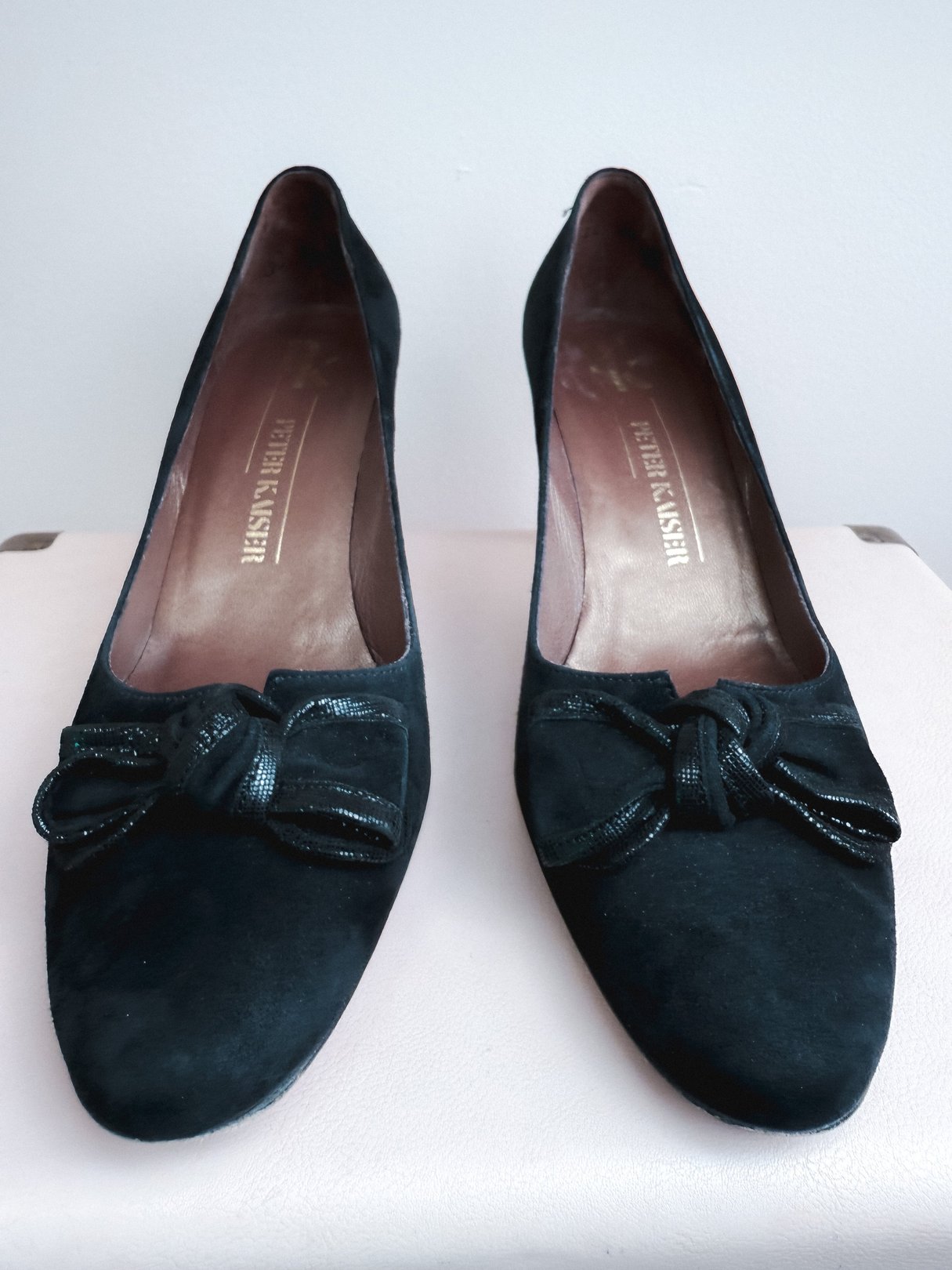 Black suede pumps featuring a bow detail, designed for women in a 1970s style.