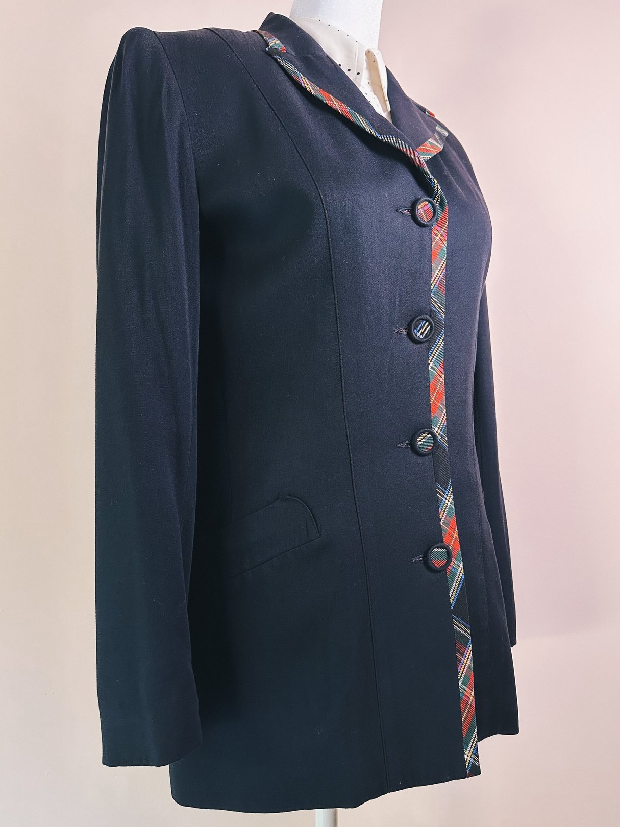 A 1990s women's black plaid suit jacket featuring a colorful tartan trim and buttons, with a tailored fit and side pockets.