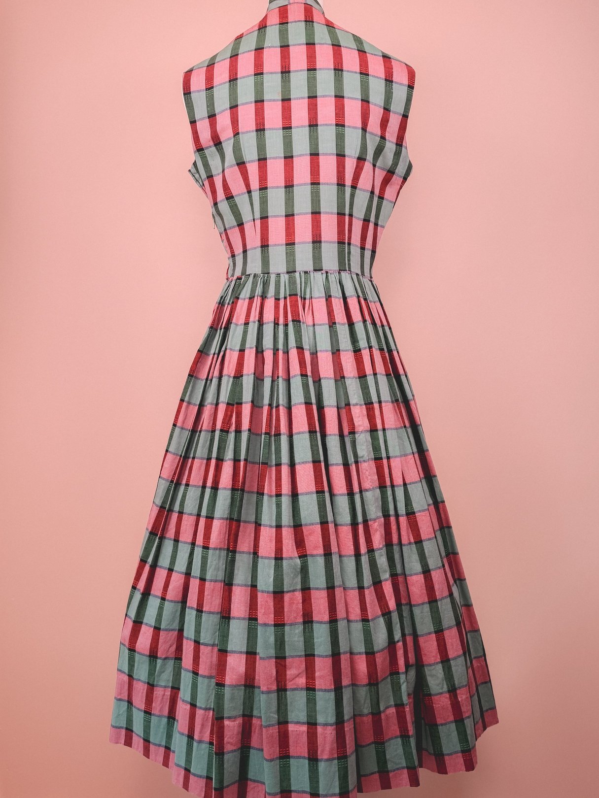 Red and green plaid dress with a fitted bodice and pleated skirt, designed for women in a 1950s style.