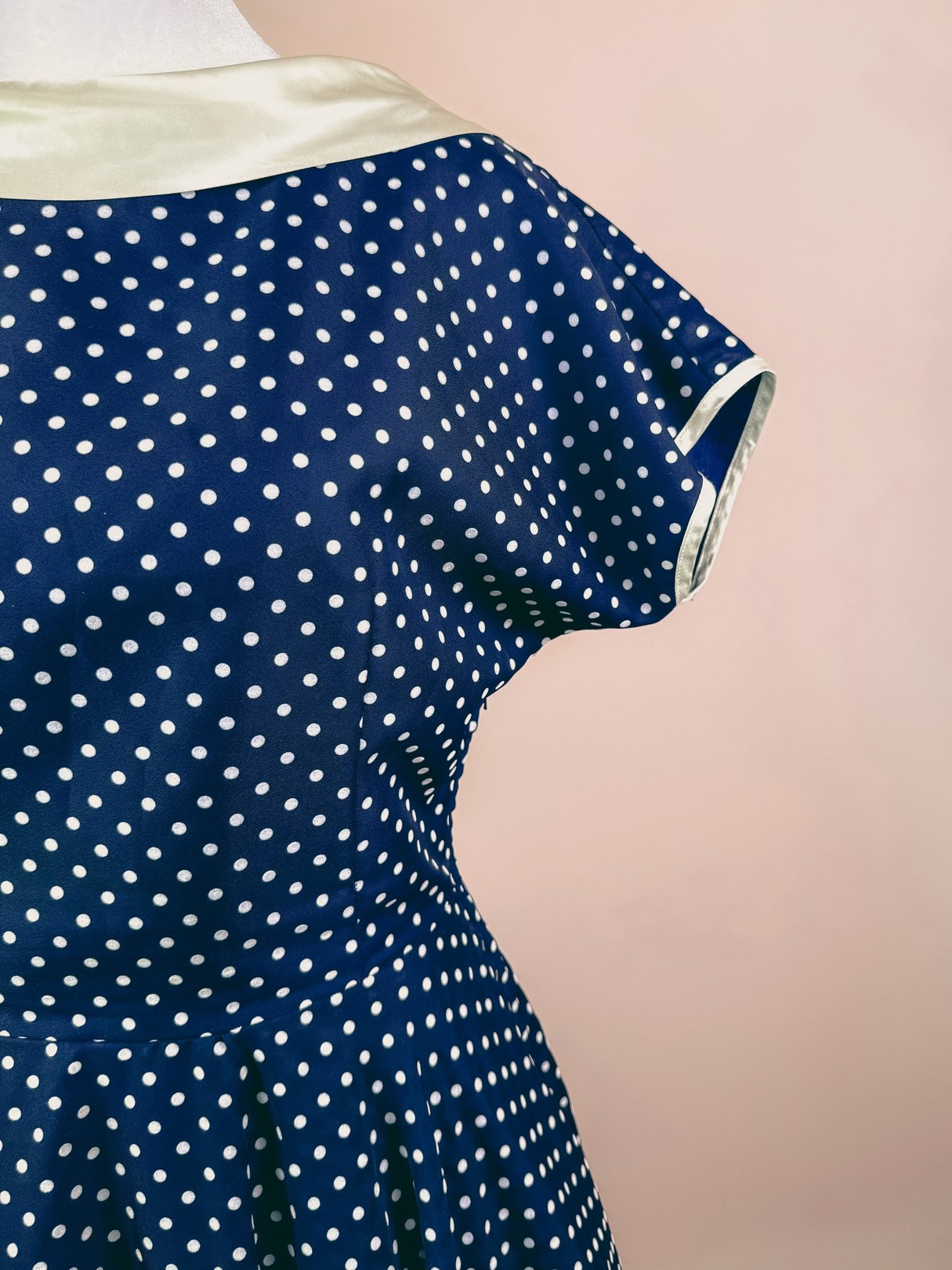 Navy blue 1950s women's dress featuring a polka dot pattern and a contrast collar.
