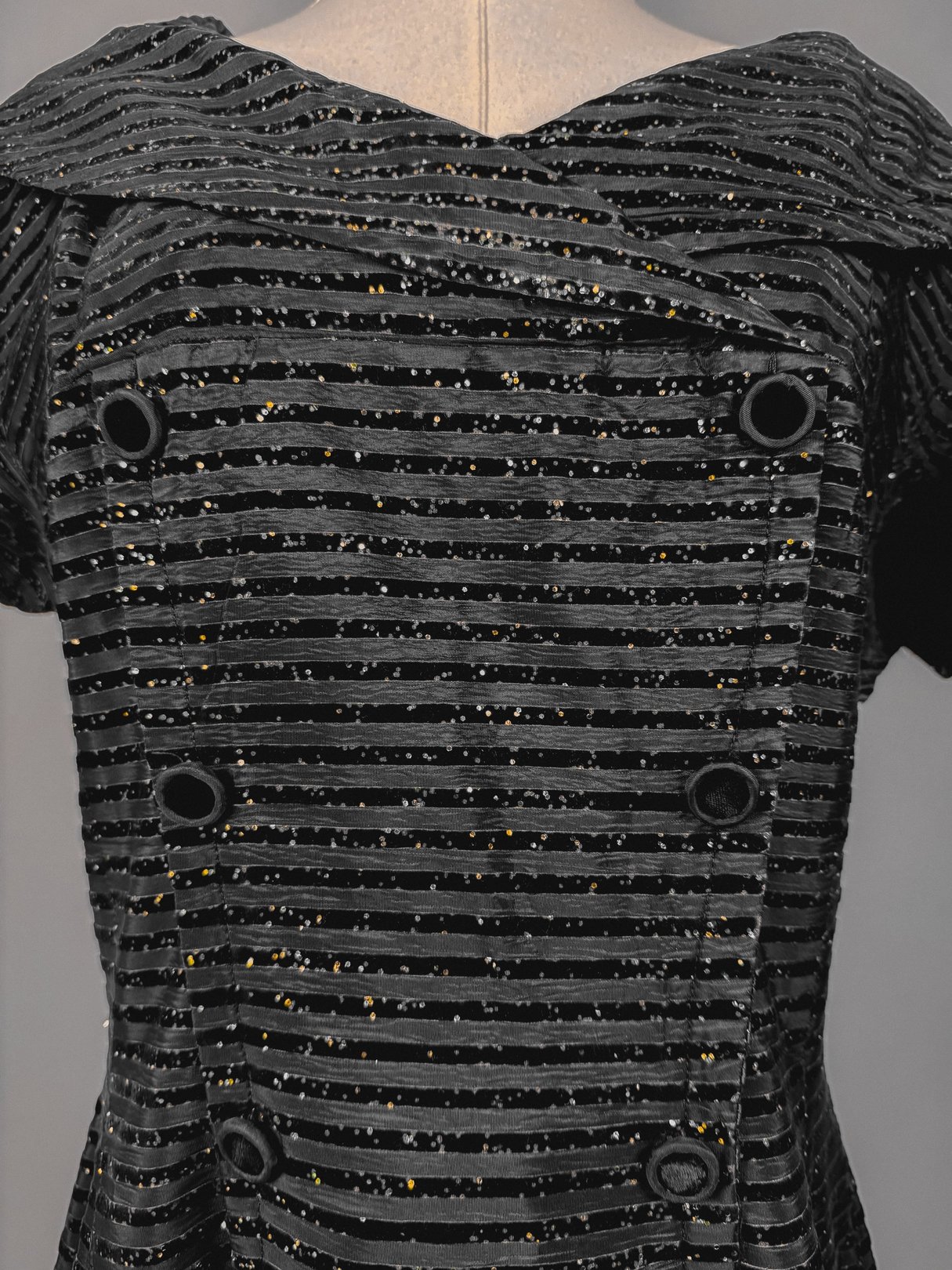 Black 1950s confetti party dress featuring a striped pattern with sparkly accents and decorative buttons.