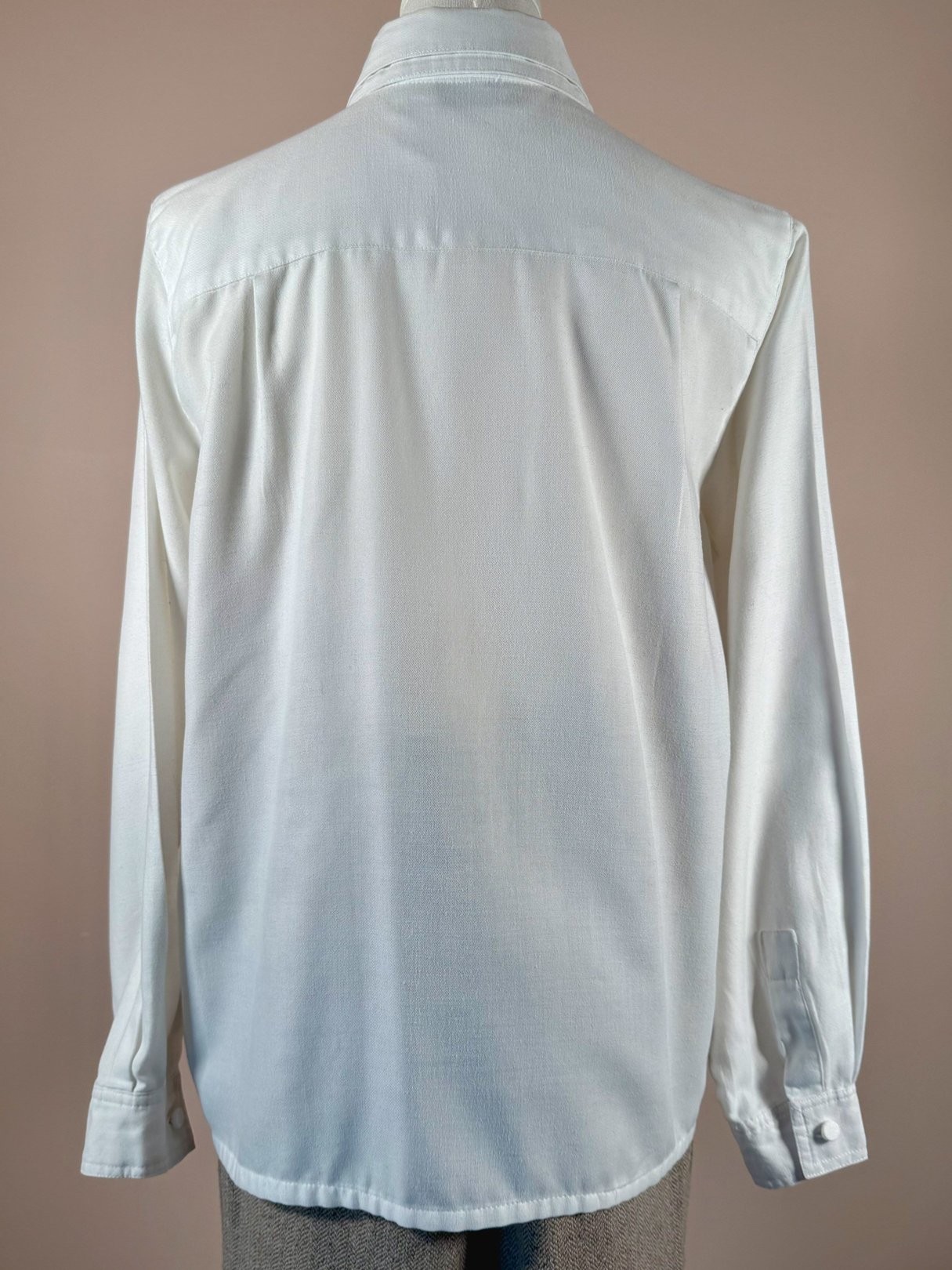 White long-sleeve women's shirt with a smooth texture, reflecting a 1970s style.