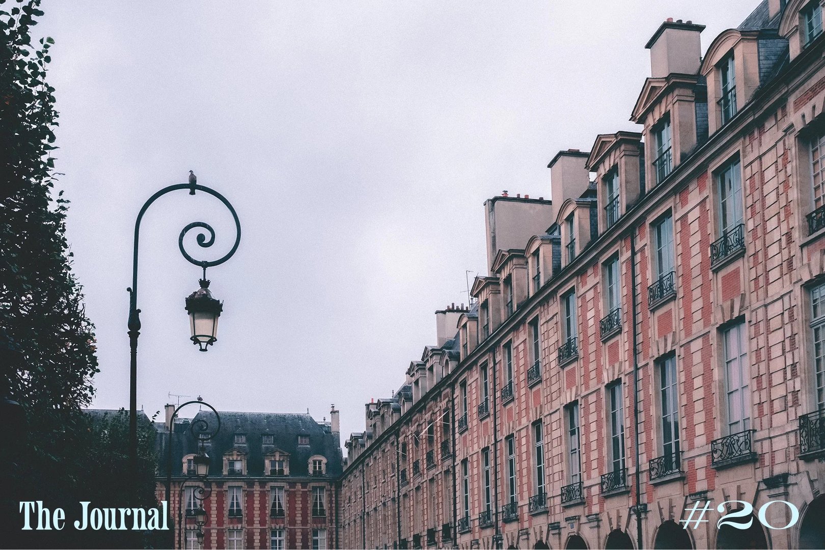Historic Parisian buildings line a cobblestone street under a cloudy sky.
