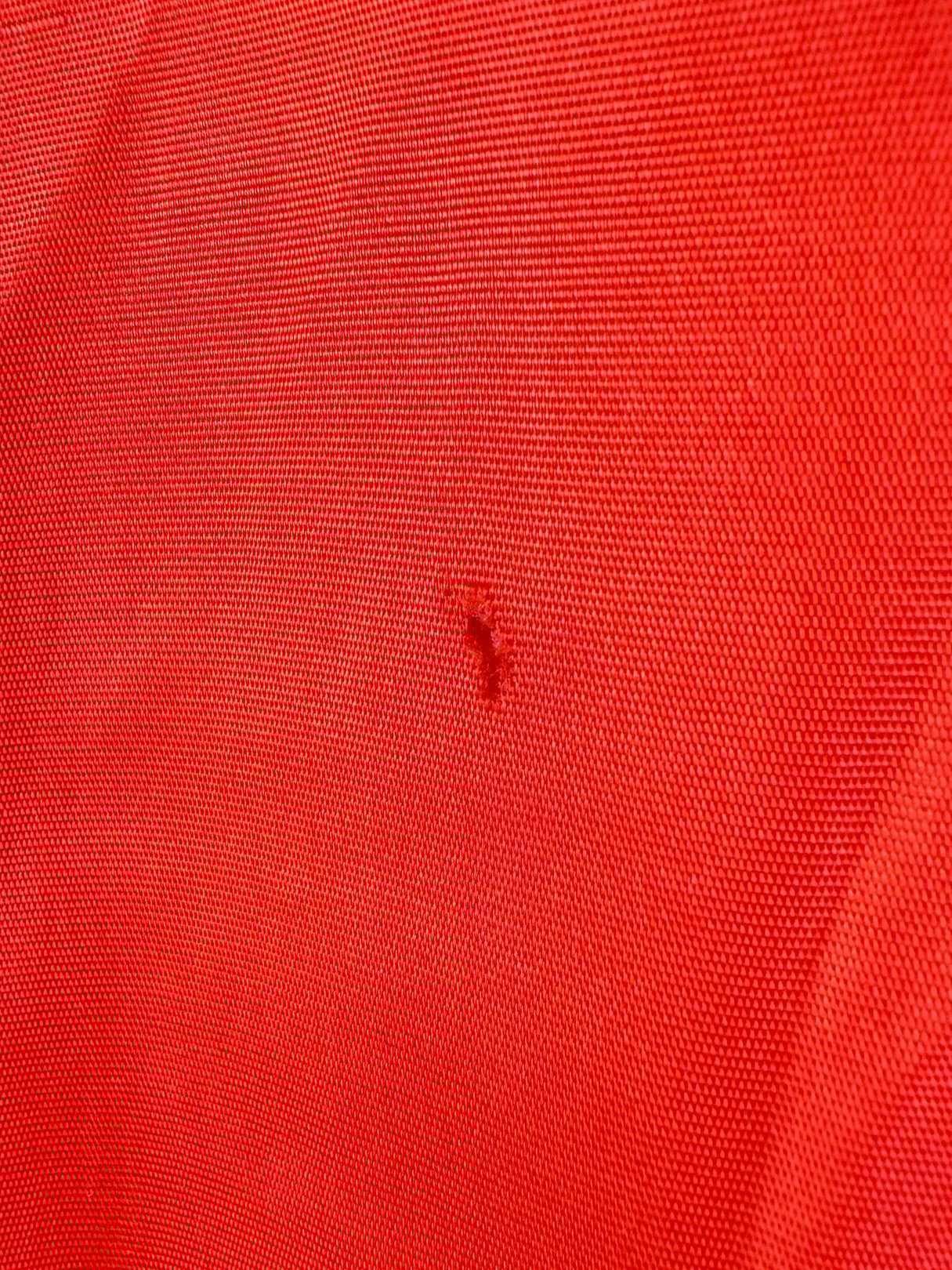 Red 1980s women's rain jacket featuring a small blemish on the fabric.