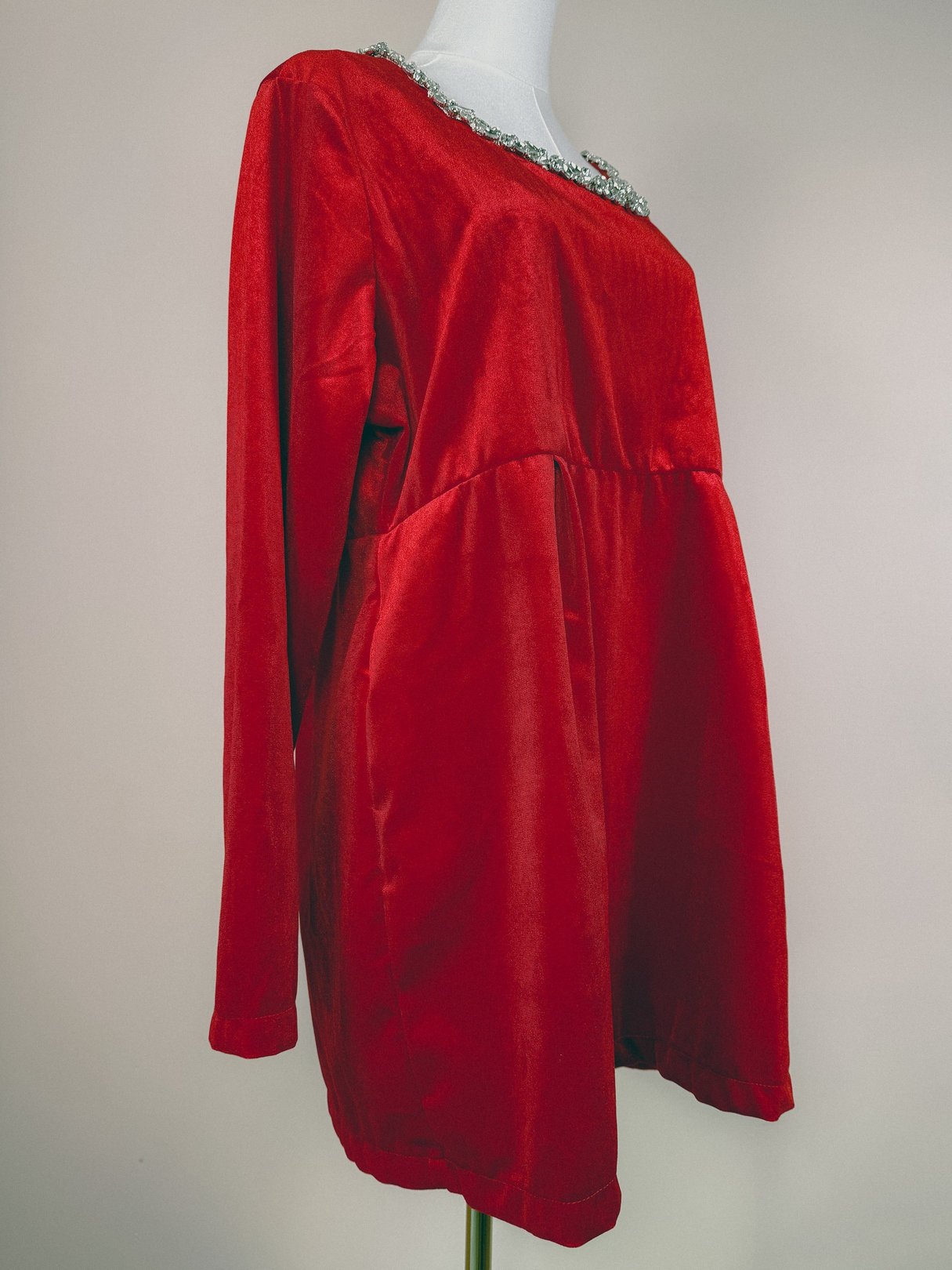 Red velvet dress with a marquise diamond neckline, featuring long sleeves and a loose-fitting silhouette, reflective of the 1970s era.