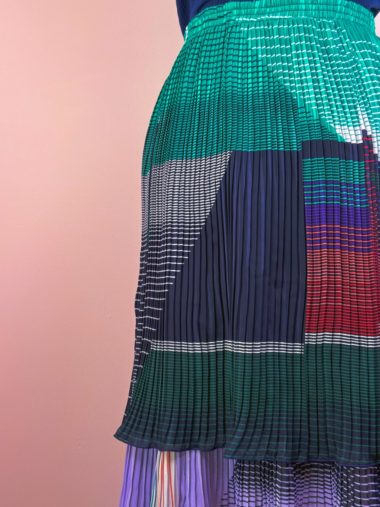 Green pleated skirt featuring a geometric color-block design, inspired by 1970s fashion for women.