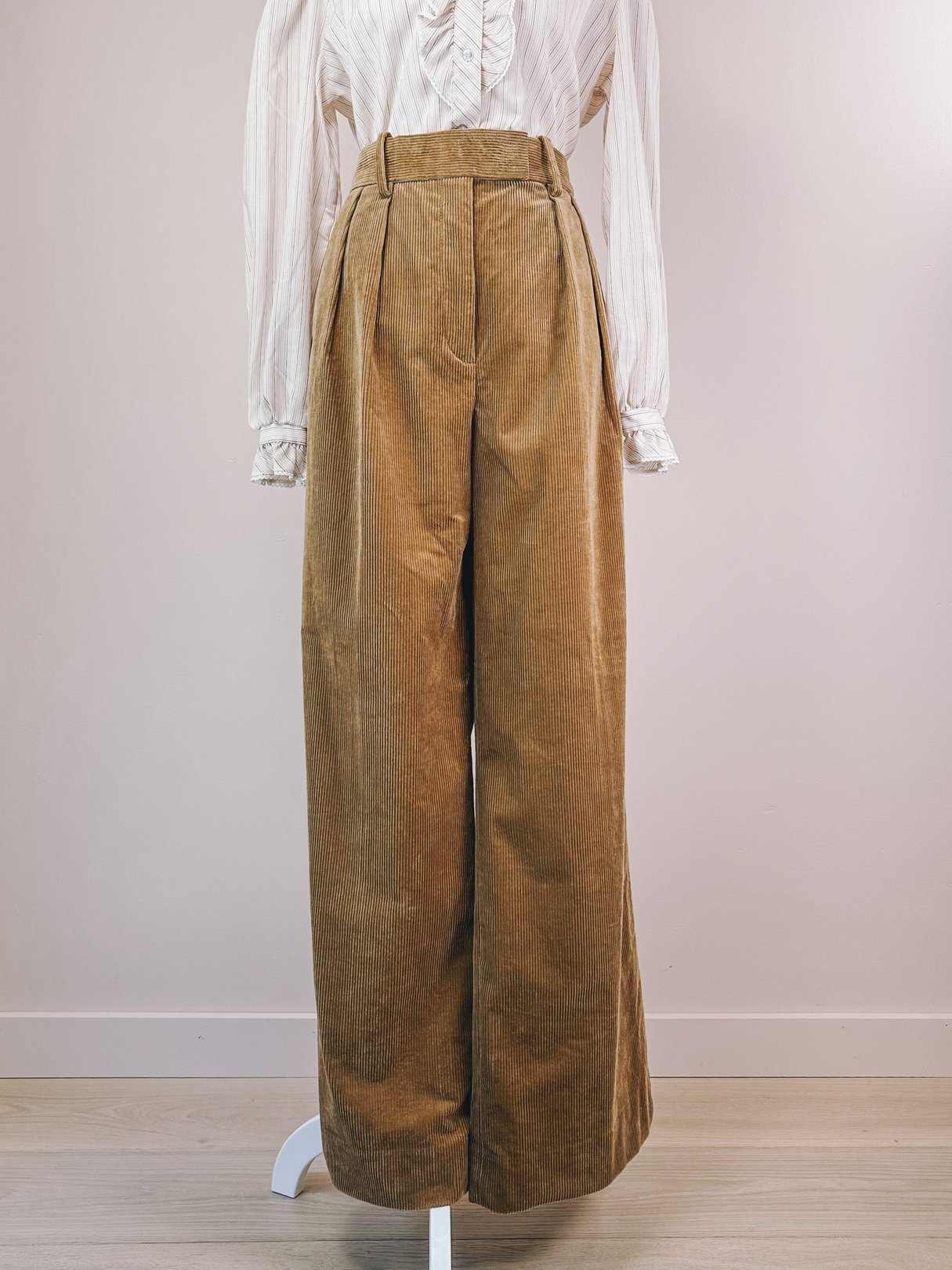 High-waisted women's corduroy pants in toast brown with pleated front, reflecting a 1970s style.