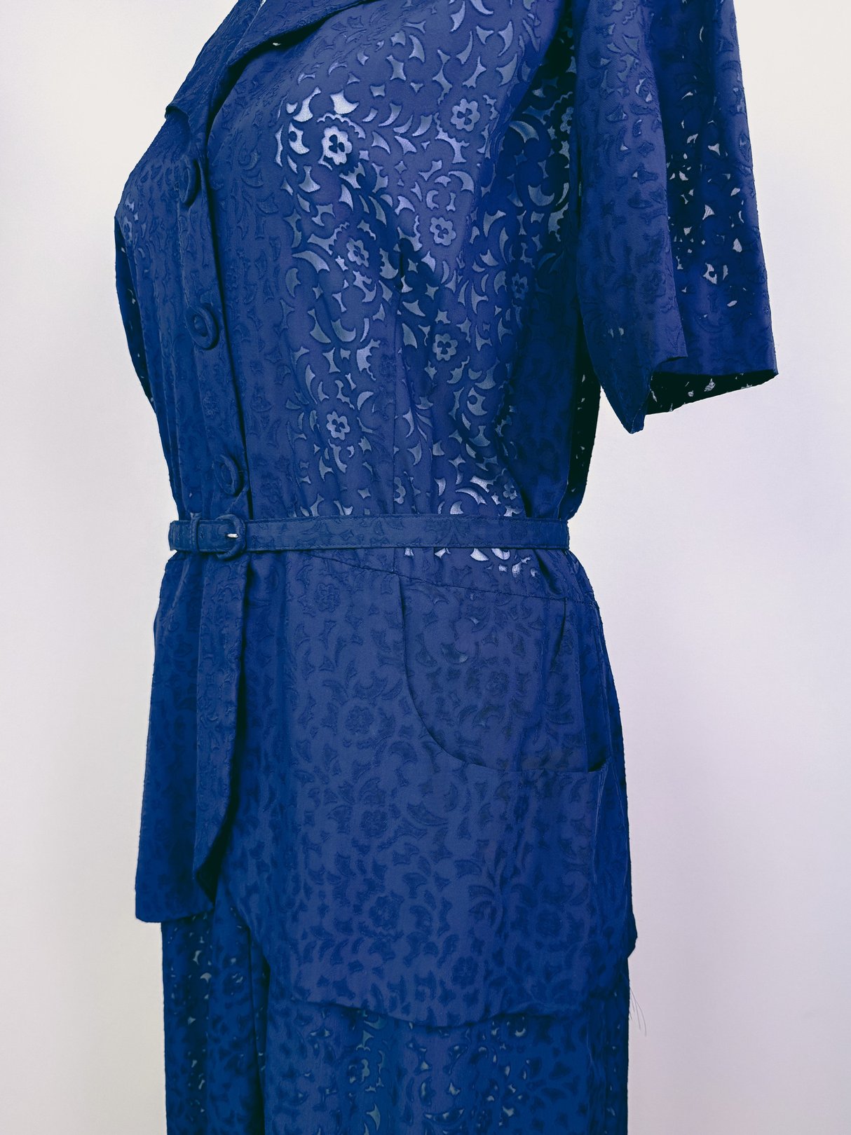 Navy blue 1940s women's French Café Dress featuring a button-up front, short sleeves, and a belted waist with floral lace detailing.