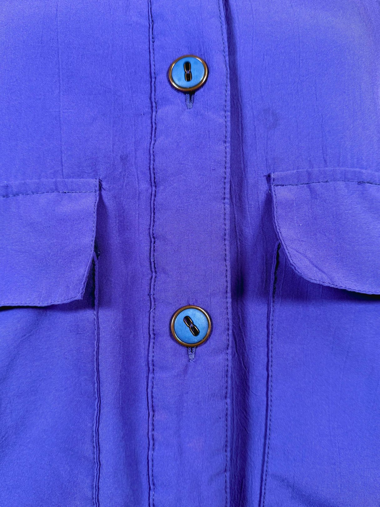 Vibrant violet 1980s women's jacket featuring two front pockets and blue buttons.
