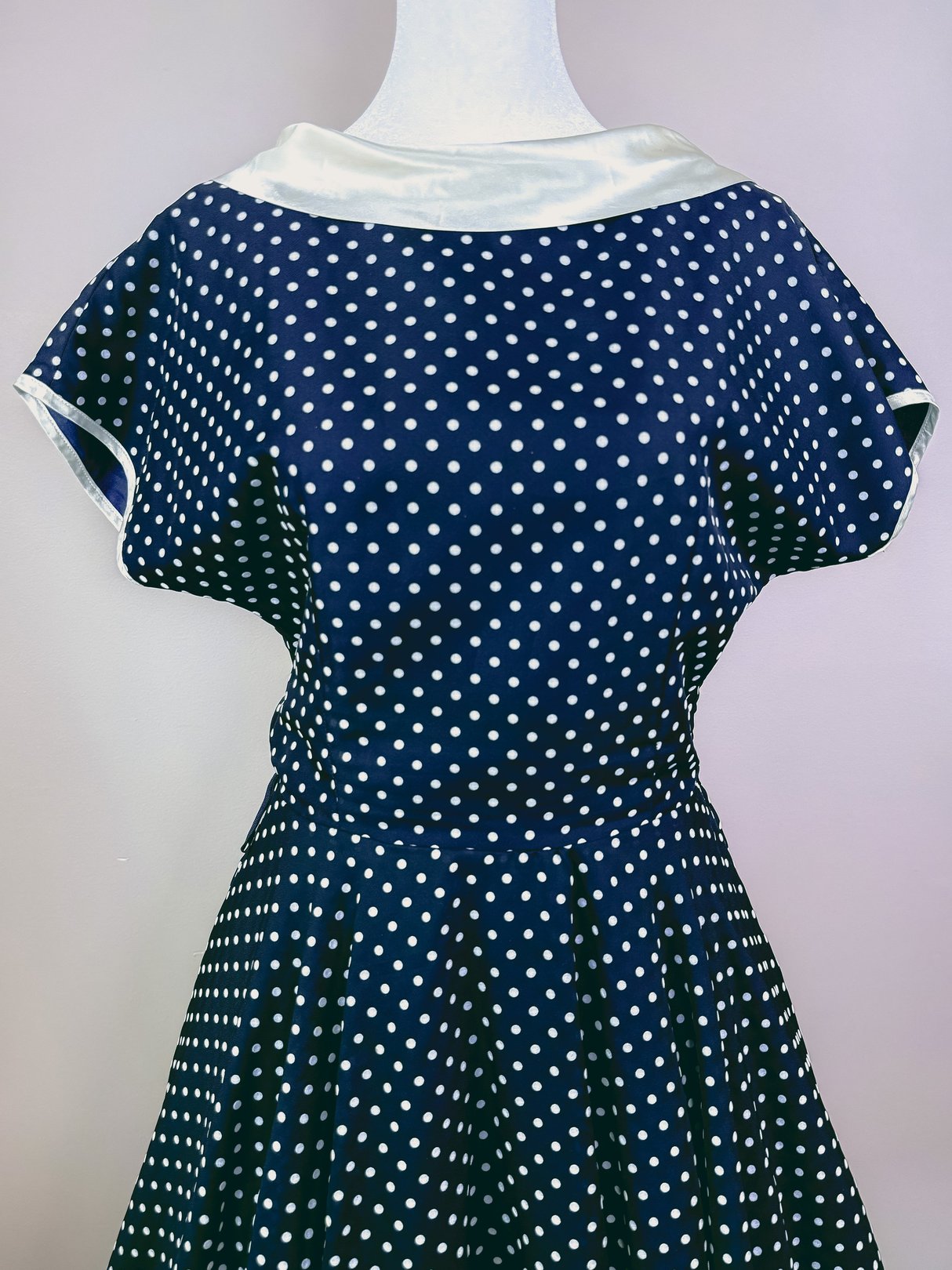 Navy blue 1950s women's dress featuring white polka dots and a satin collar.