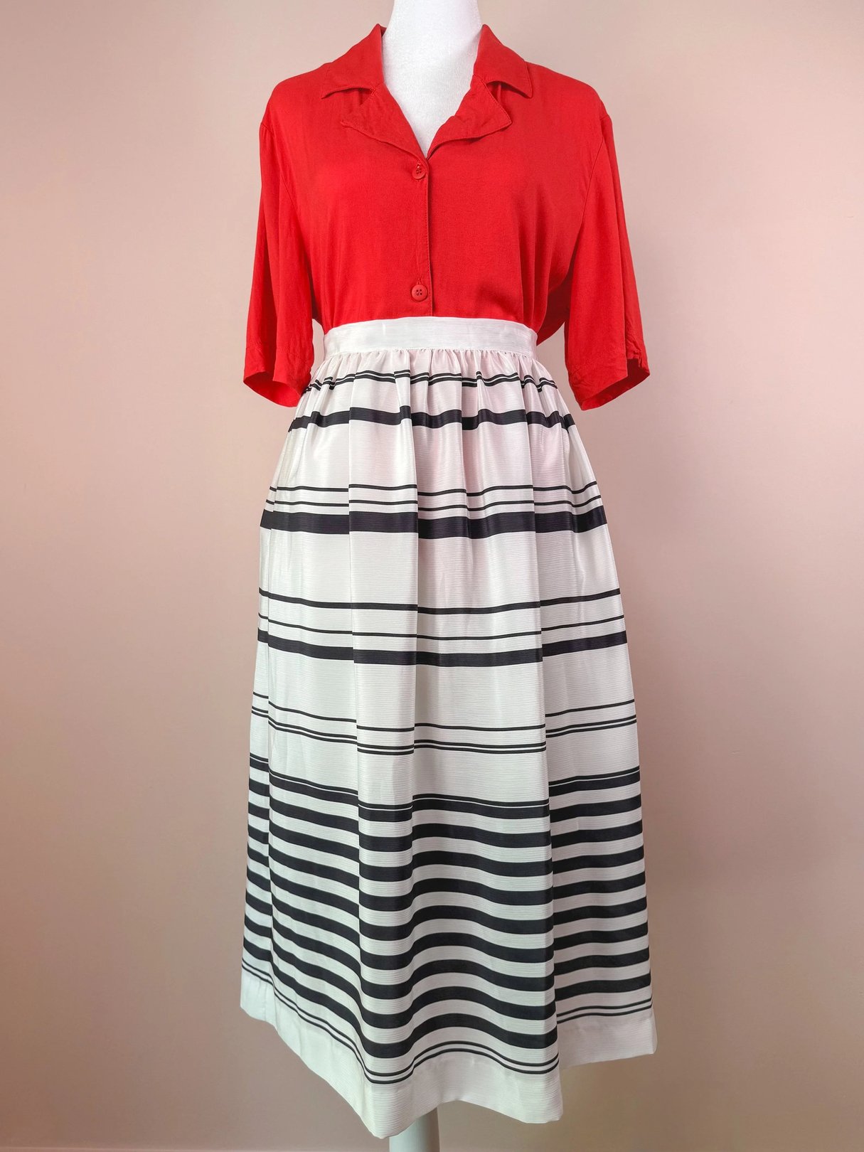 Red short-sleeve blouse paired with a white and black striped skirt.