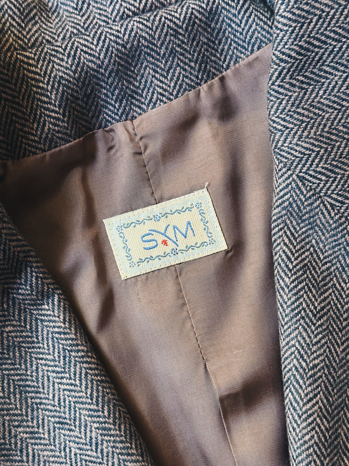 Mauve pink women's tweed blazer from the 1970s featuring a herringbone pattern and an internal label.
