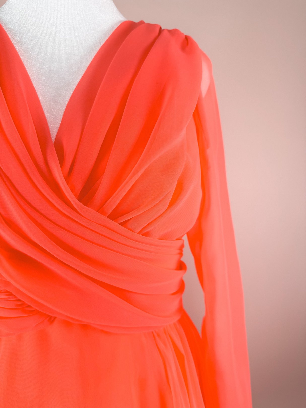 Coral Soirée Dress featuring a draped design and long sleeves, reflecting 1960s style for women.