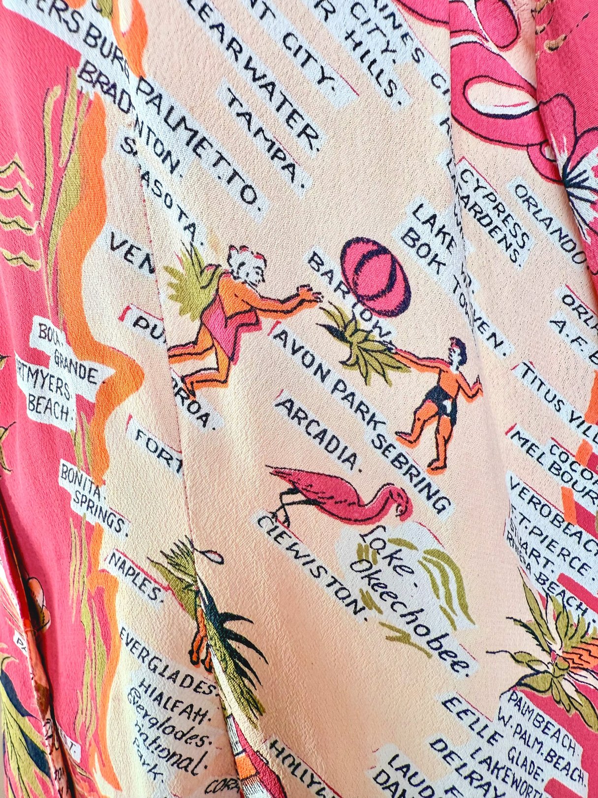 1970s women's top in white featuring a colorful Florida map print with illustrations of people and palm trees.