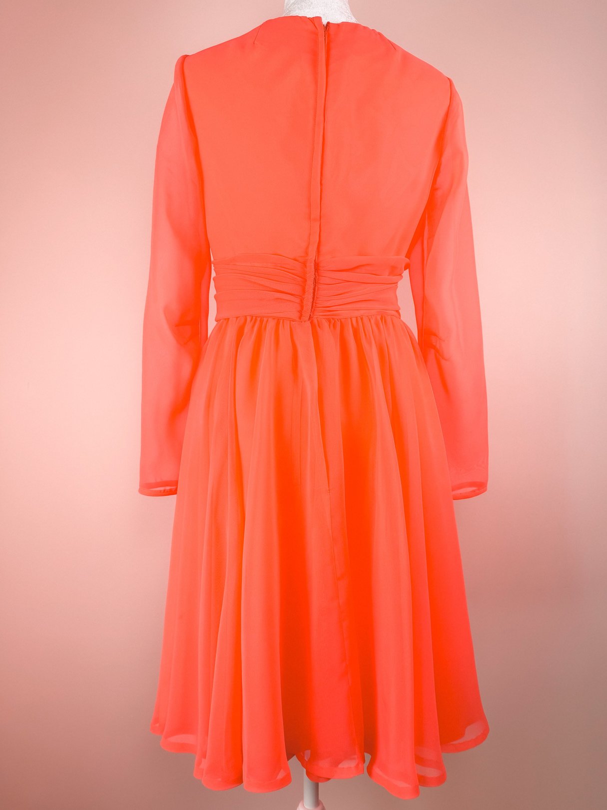 Coral Soirée Dress featuring long sleeves, a cinched waist, and a flared skirt, typical of 1960s women's fashion.