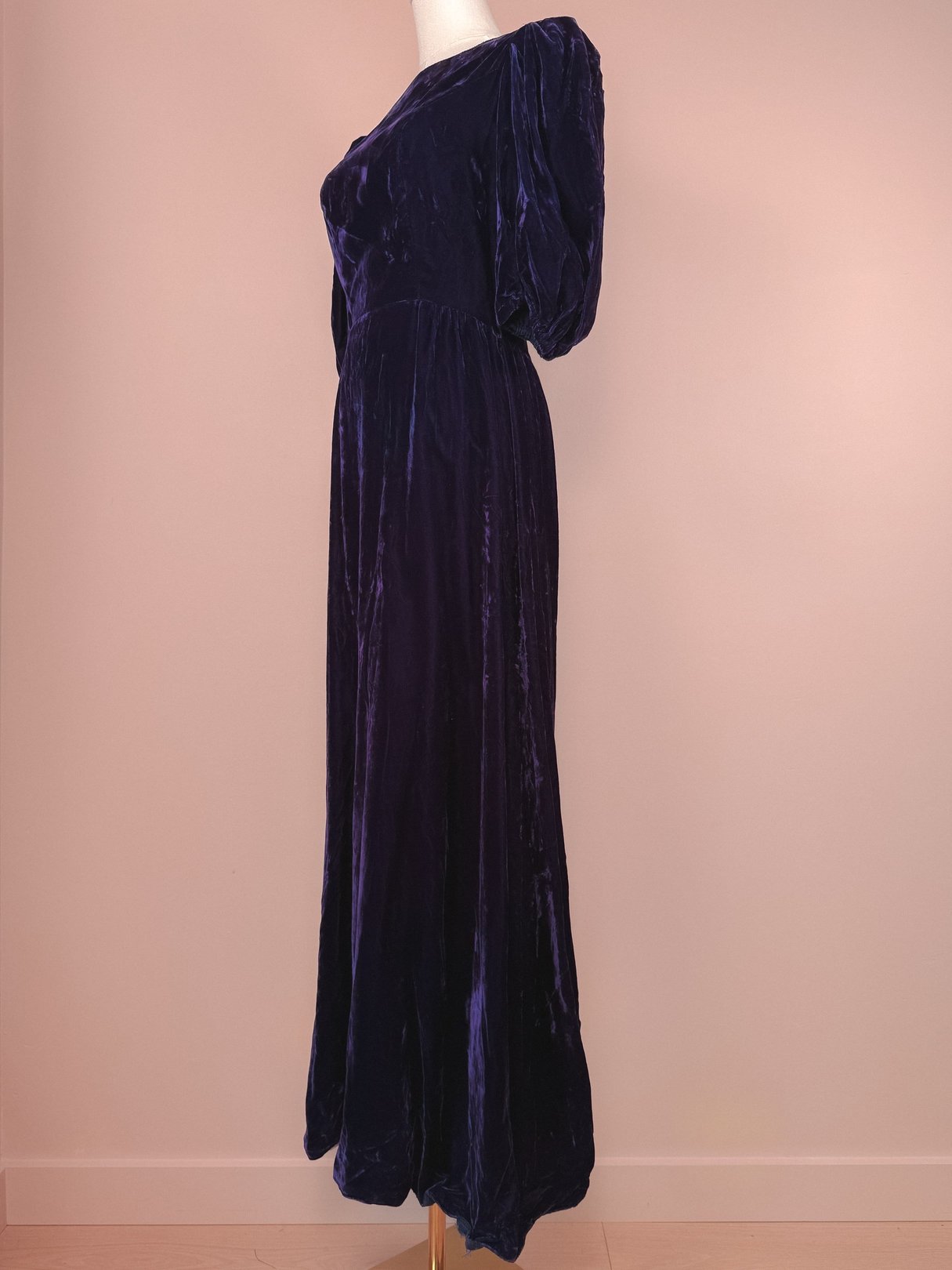 A purple velvet dress with a fitted bodice and puff sleeves, styled in a 1960s silhouette.