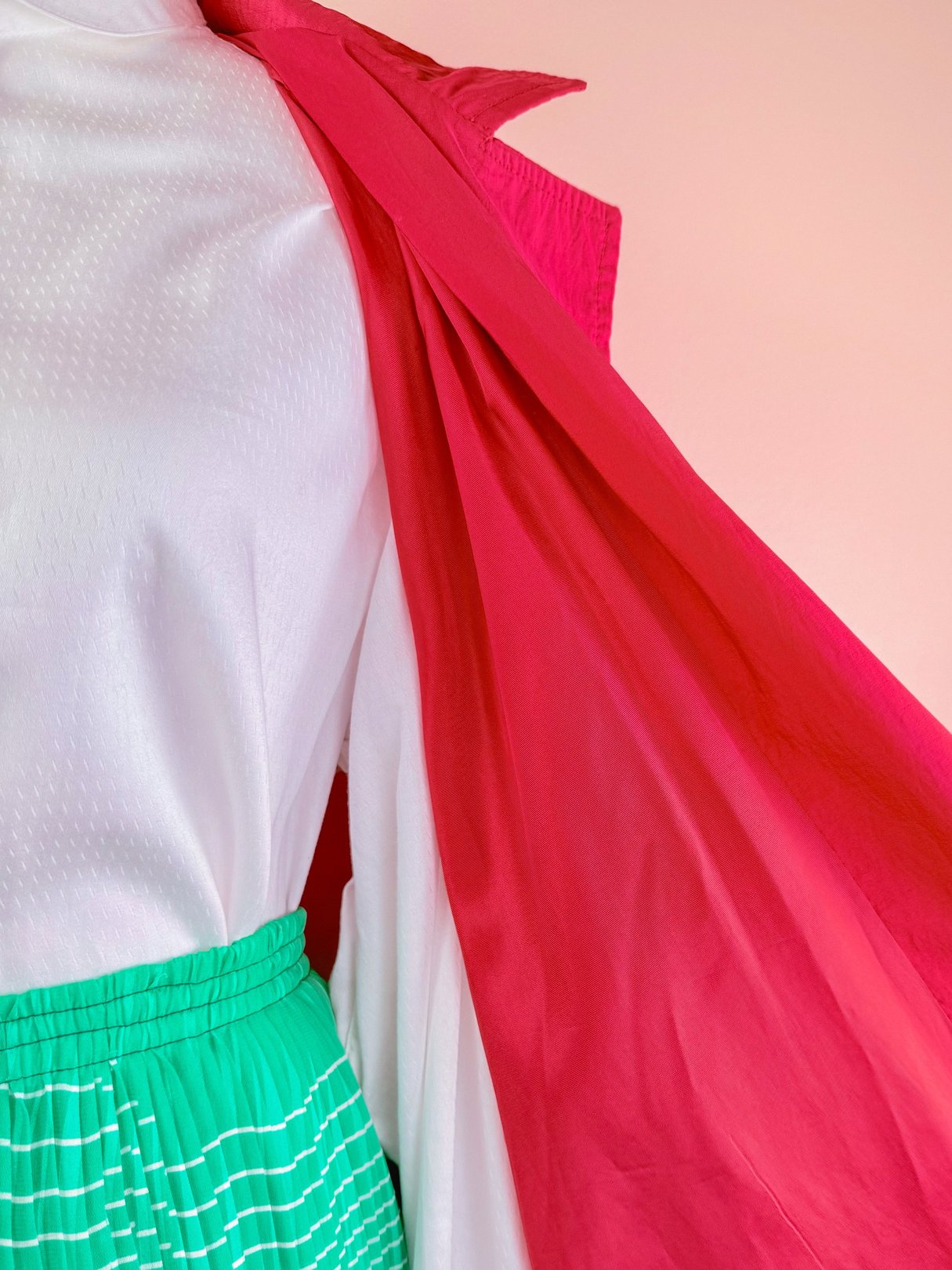 Red 1980s women's Poppy Forecast rain jacket displayed over a white top and green skirt with white stripes.