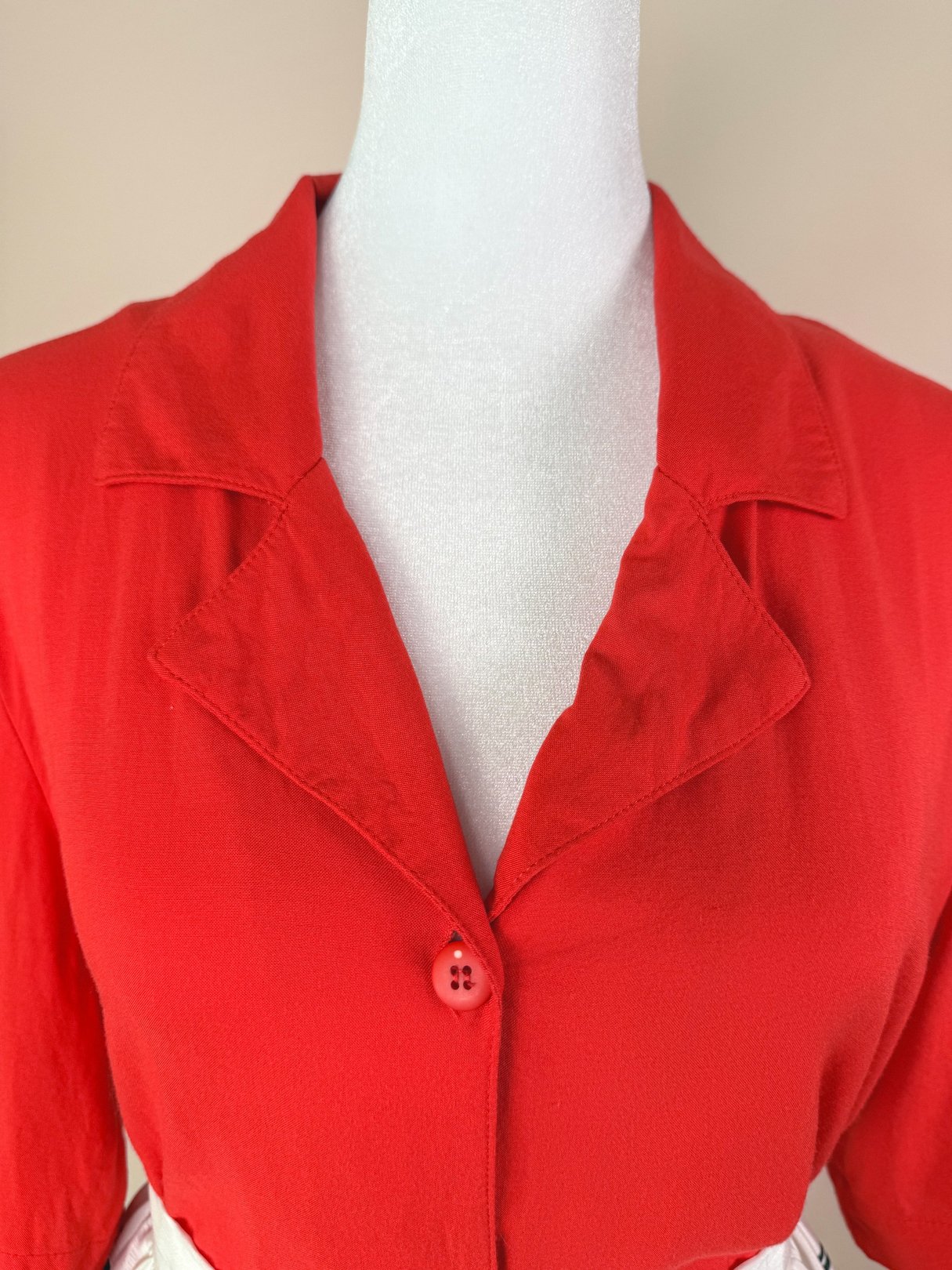 Bright red 1980s women's top featuring a notched collar and a single button closure.