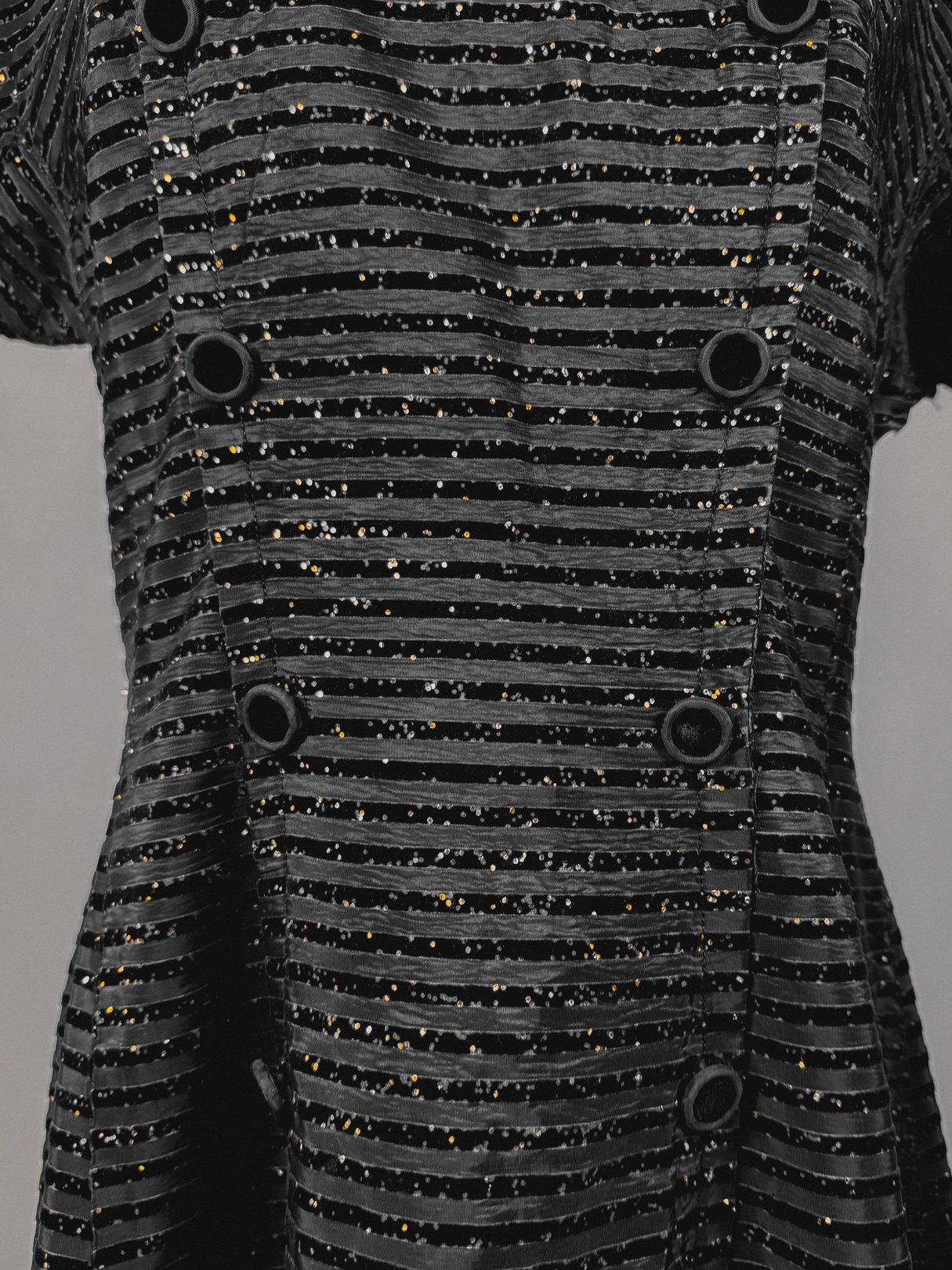 1950s women's black confetti party dress featuring a textured striped pattern and decorative buttons.