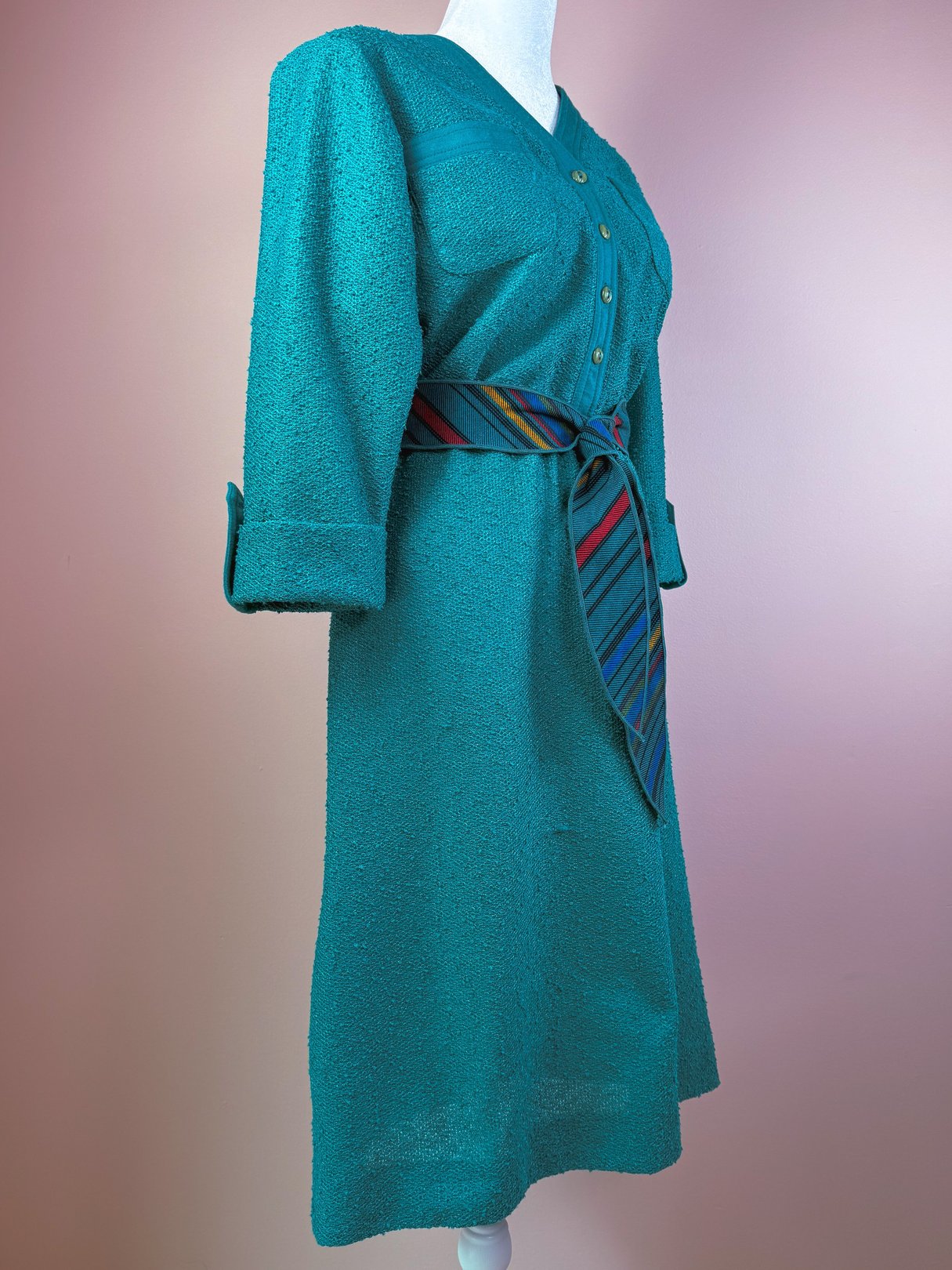 Teal 1980s women's dress with a button-down front and a multicolored striped belt.