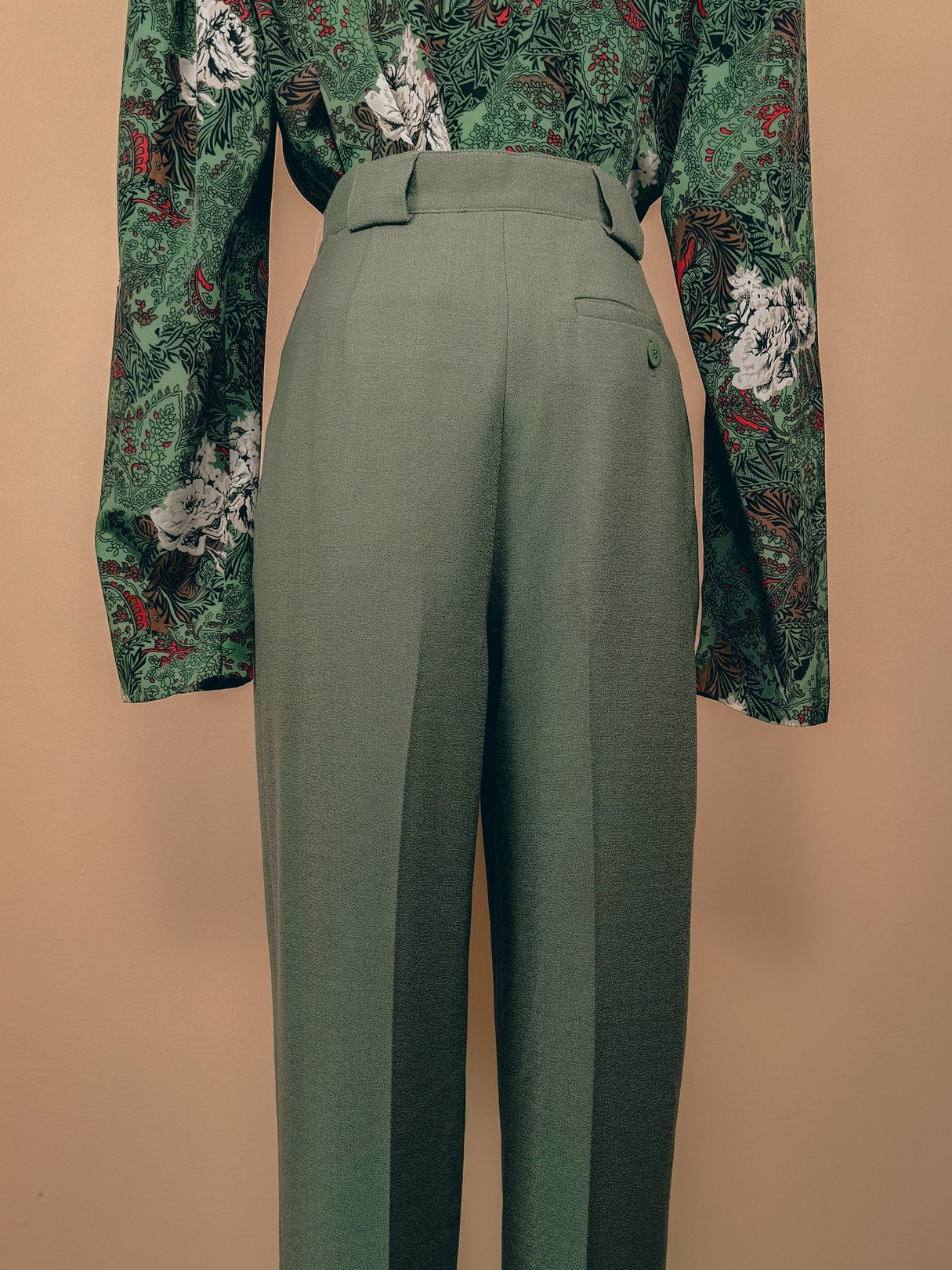 High-waisted sage green pleated trousers for women, featuring a classic 1980s design.