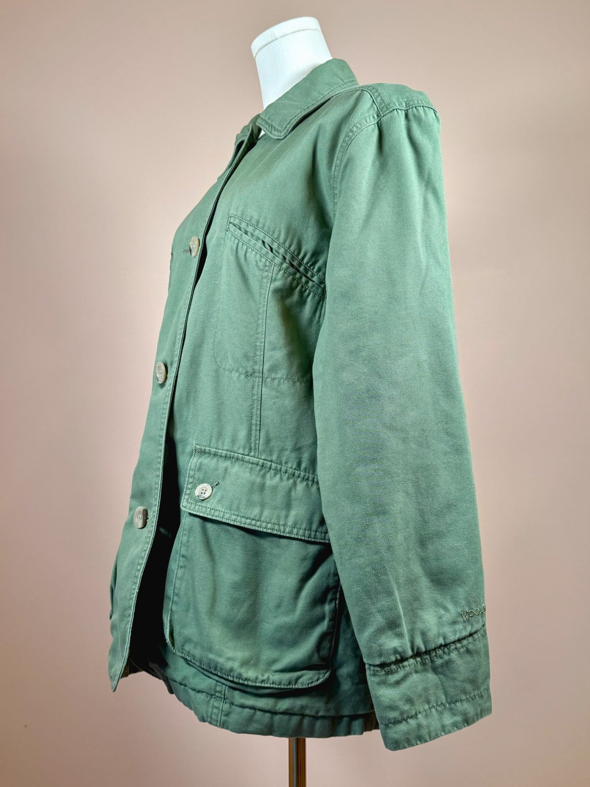 Sage quilted women's jacket from the 1970s with a button-up front and side pockets.