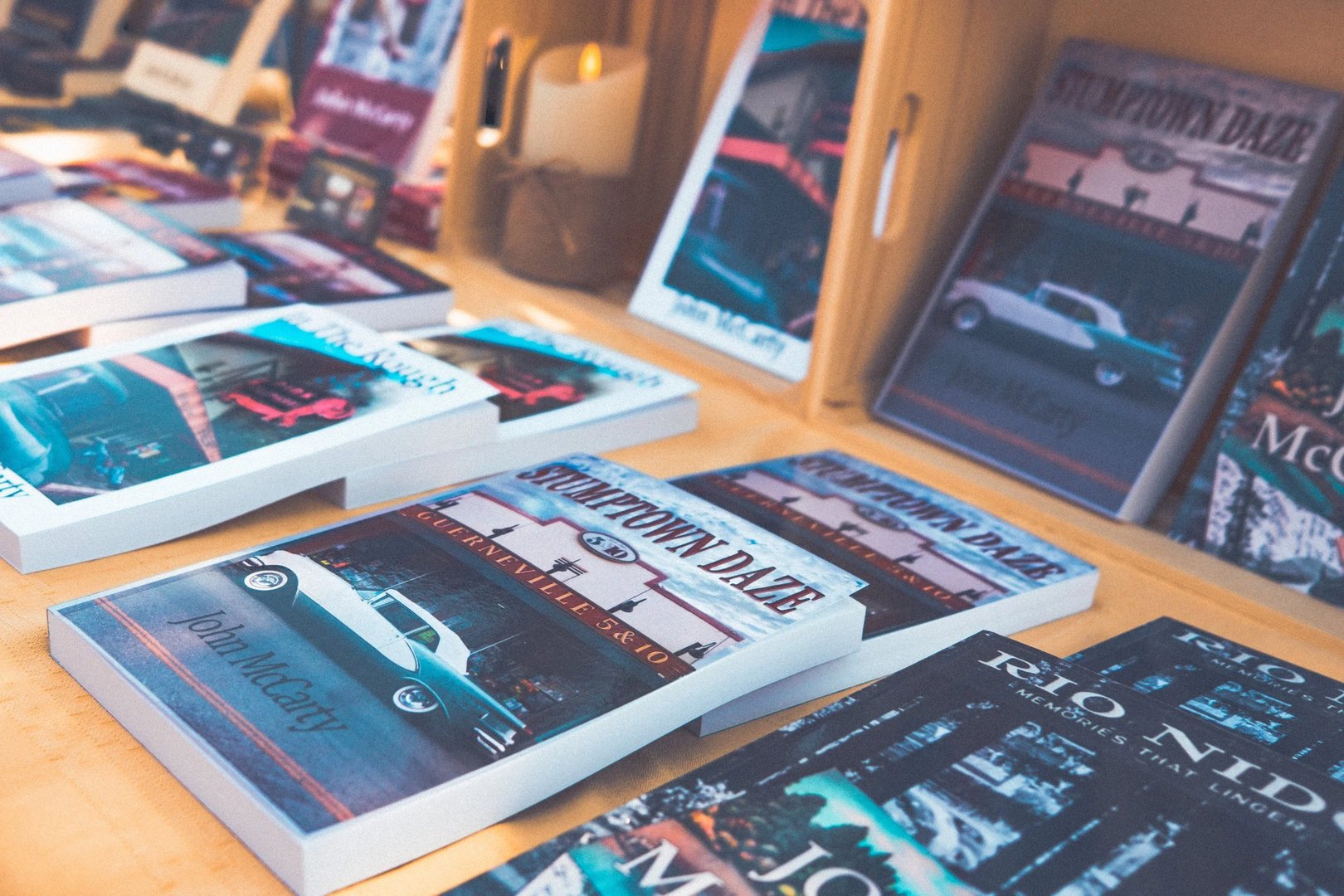 A selection of books displayed on a wooden table, featuring titles such as "Stumptown Daze" by John McCarthy.