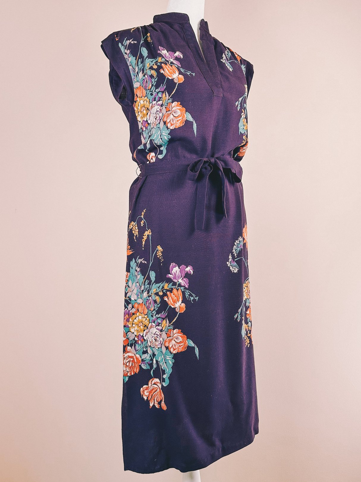 Purple 1970s women's dress featuring floral prints and a belted waist.