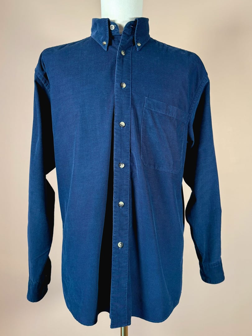 Navy blue men's corduroy shirt from the 1990s featuring a button-up front and a left chest pocket.
