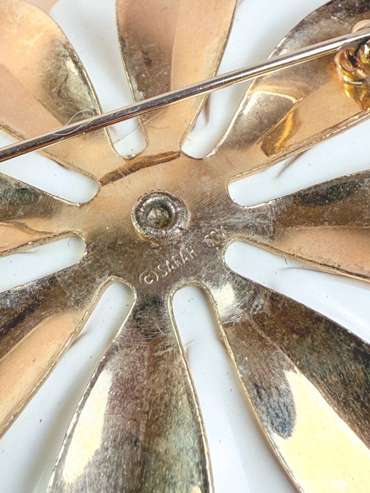 A gold Gilded Dahlia brooch from the 1950s featuring a floral design with layered petals.