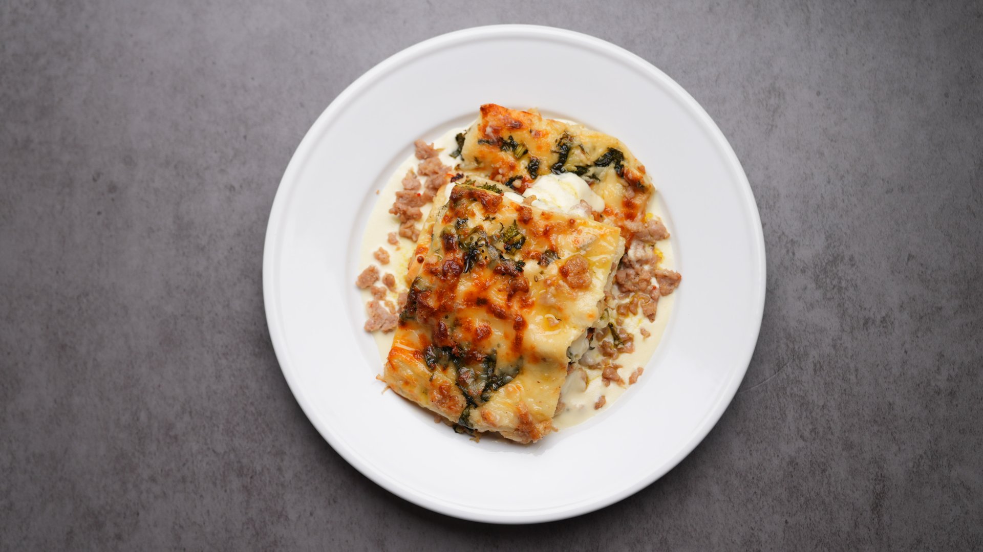 Layers of roasted broccoli rabe tossed in extra virgin olive oil and fresh lemon zest, savory Italian chicken sausage, and delicate pasta sheets, all nestled between creamy, nutmeg-kissed béchamel and a light sprinkle of mozzarella.