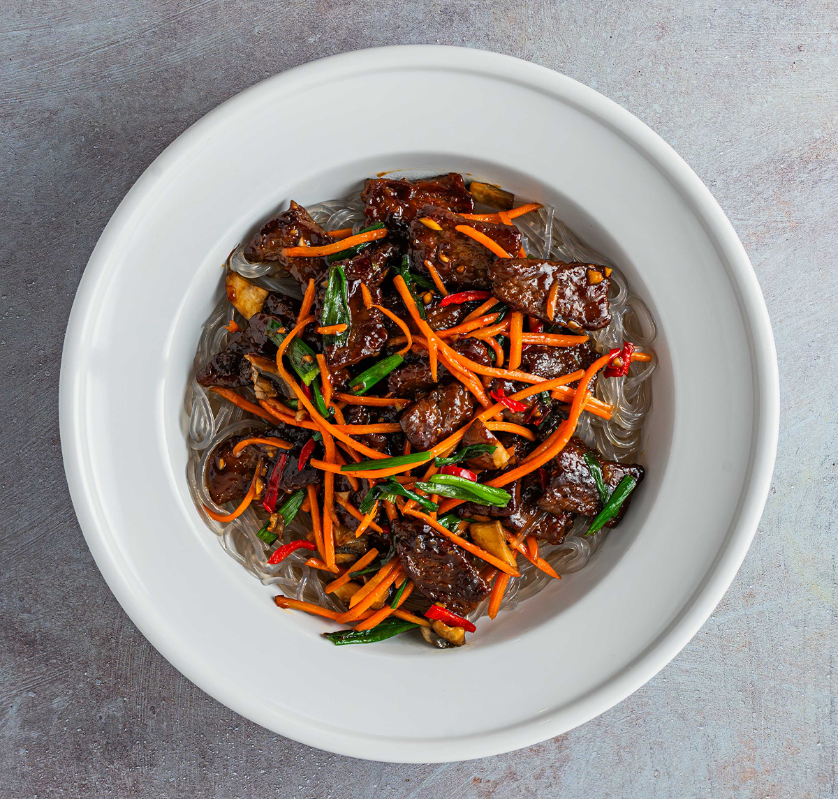 Tender, juicy steak tossed with silky sweet potato glass noodles, earthy crimini mushrooms, crisp shredded carrots, and fresh green scallions.