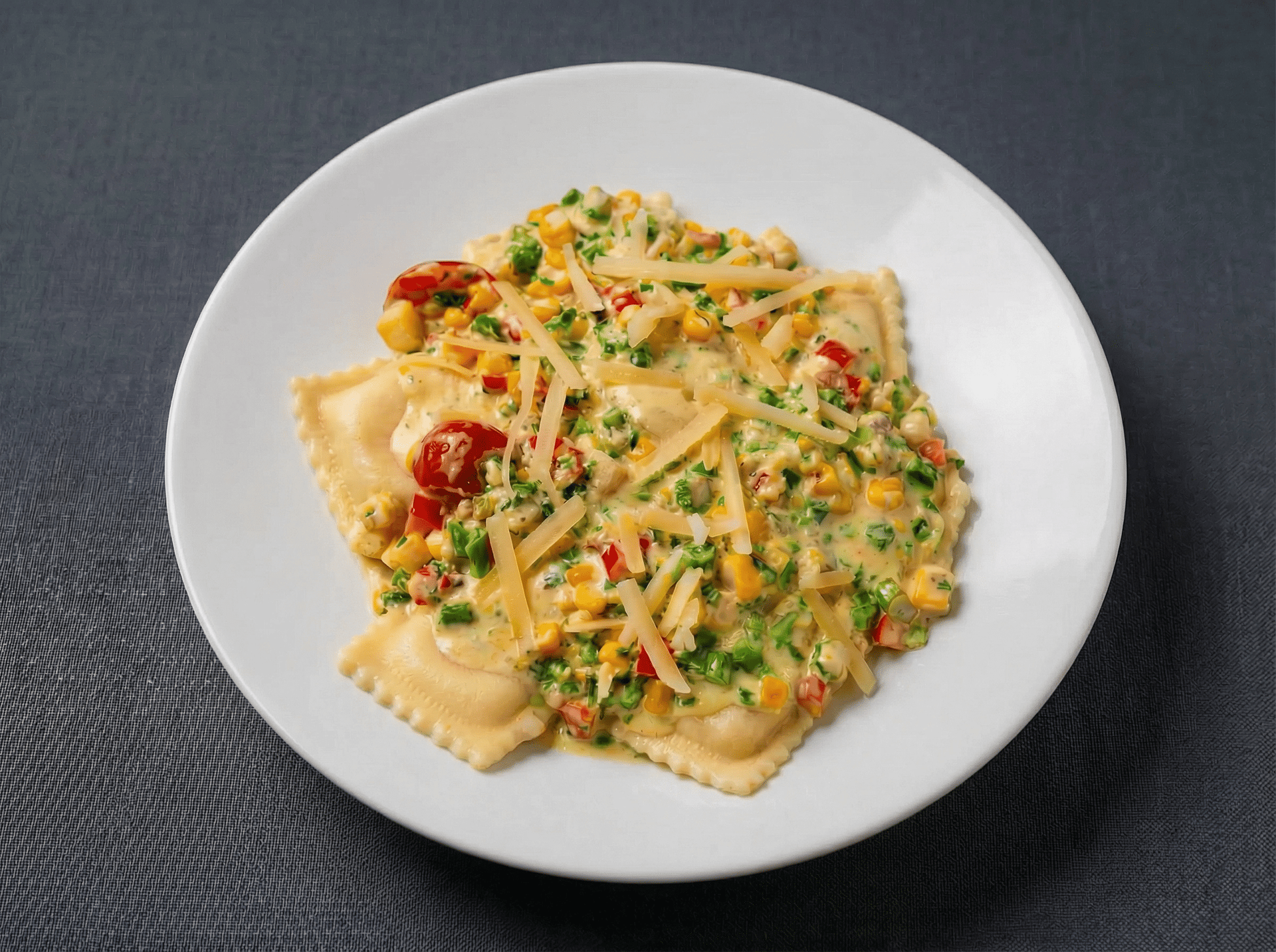 Handmade ravioli stuffed with a luxurious four-cheese blend of ricotta, mozzarella, fontina, and pecorino, nestled in a silky butter cream sauce alongside roasted corn, zucchini, summer squash, red bell peppers, asparagus, and sweet roasted tomatoes.