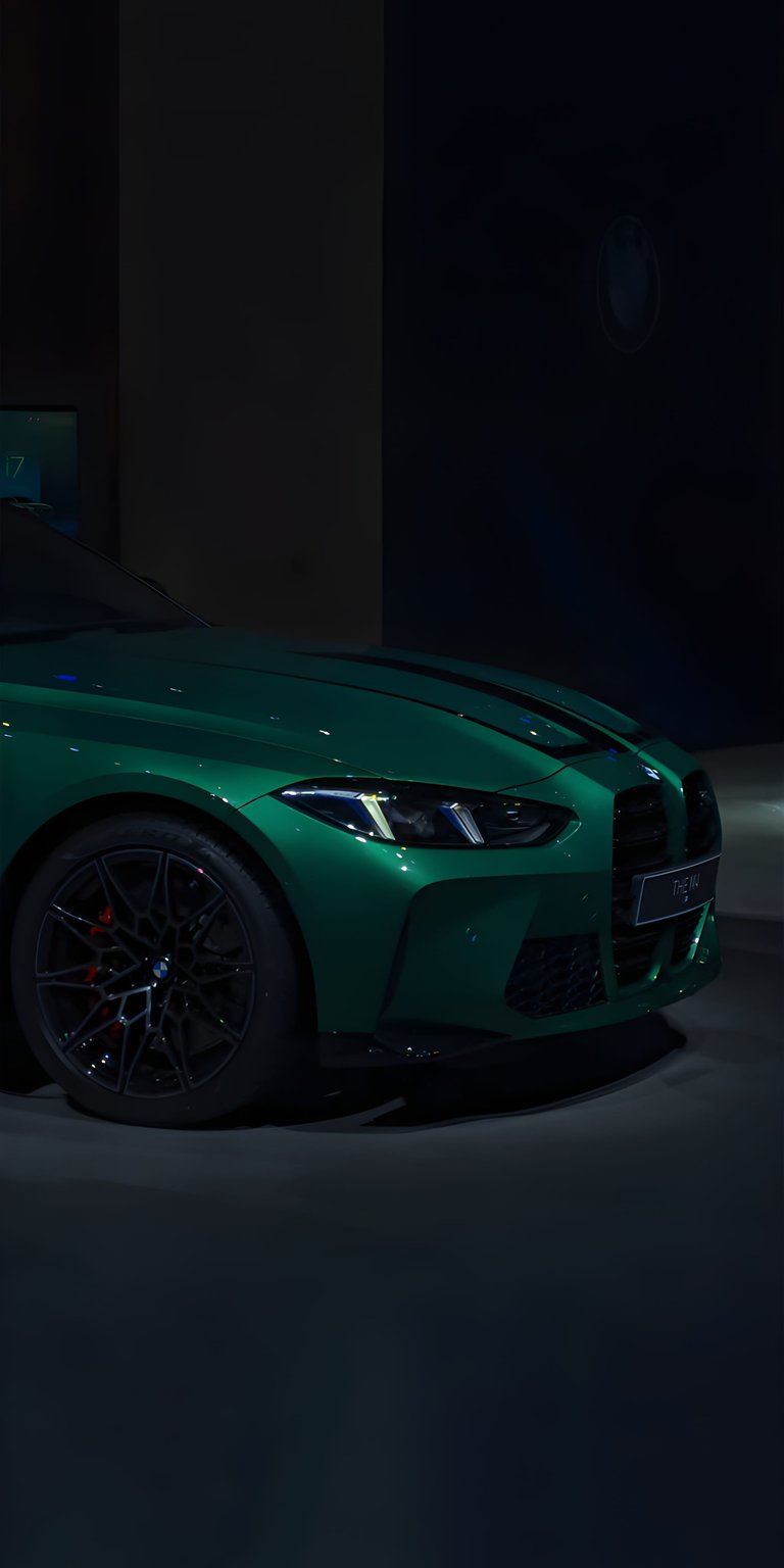 BMW M4 4K wallpaper featuring a deep green finish, aggressive front grille, and dramatic studio lighting. This aesthetic wallpaper enhances your iPhone lock screen and home screen with bold shadows and sharp performance styling.