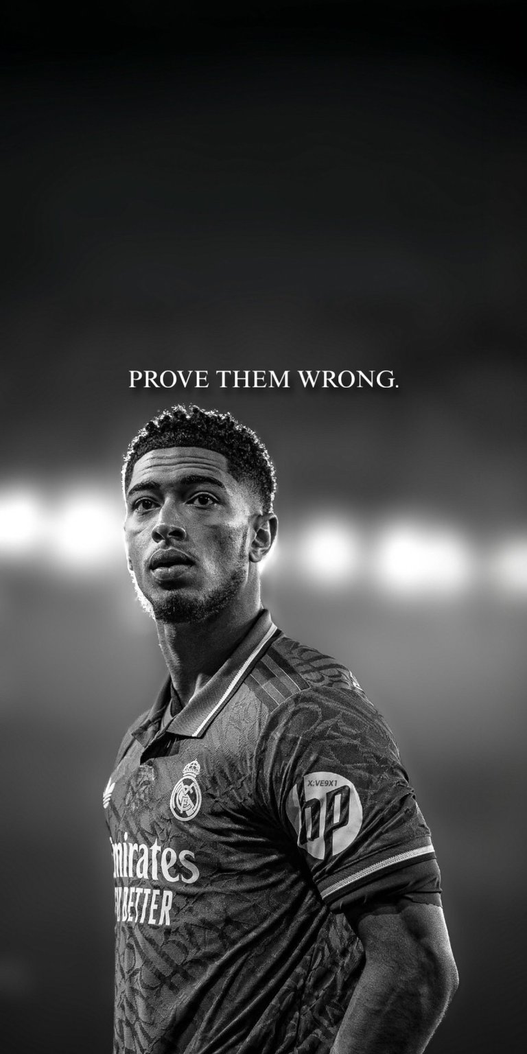 This 4K OLED wallpapers design features a black and white portrait of Jude Bellingham for your iPhone. The wallpaper showcases high-contrast monochrome tones and a blurred stadium lighting background with motivational text.