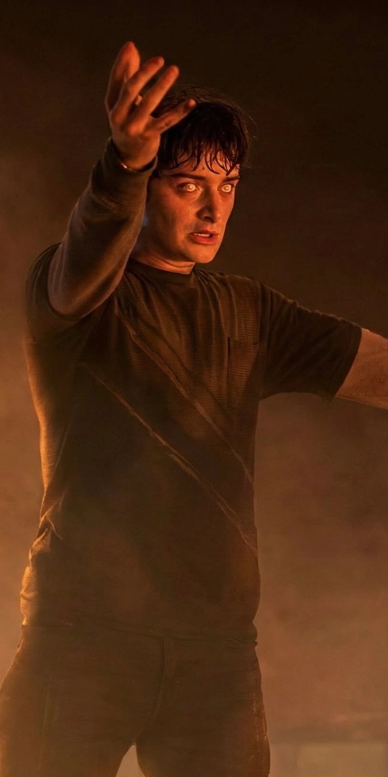 Download this awesome Sebastian Stan 4K wallpaper for your iPhone, featuring his glowing eyes and raised hand amidst a fiery scene. This wallpaper captures Stan in a dark t-shirt and jeans.