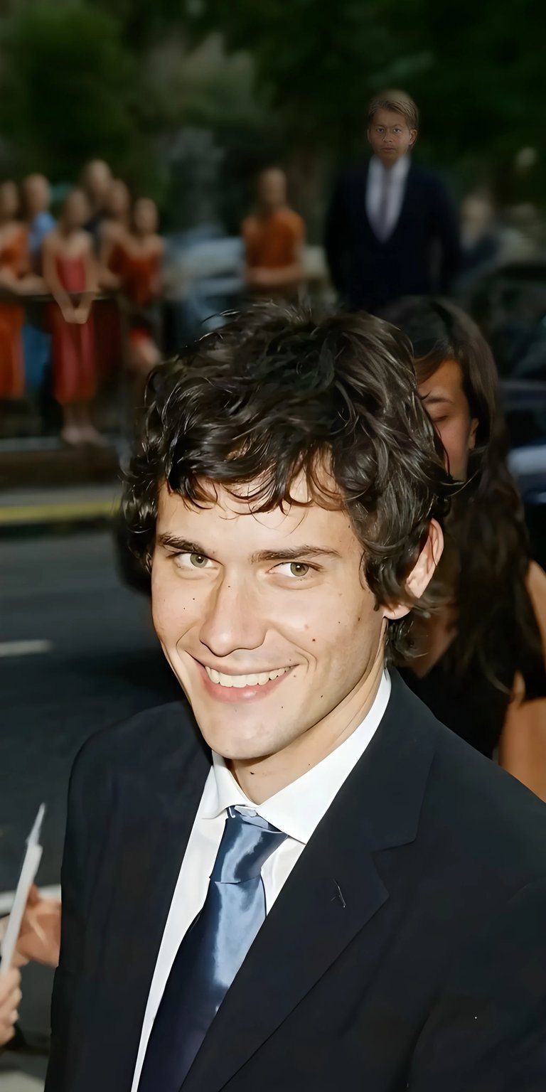 Get this stunning Brian Moser wallpaper for your iPhone in 4K resolution! This wallpaper features his signature curly hair, a dark suit, and a shiny blue tie.