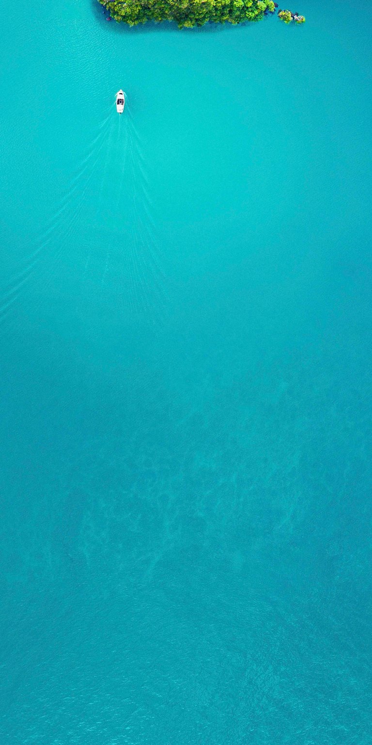 Boat cruising in a  turquoise-blue ocean water wallpaper iPhone
