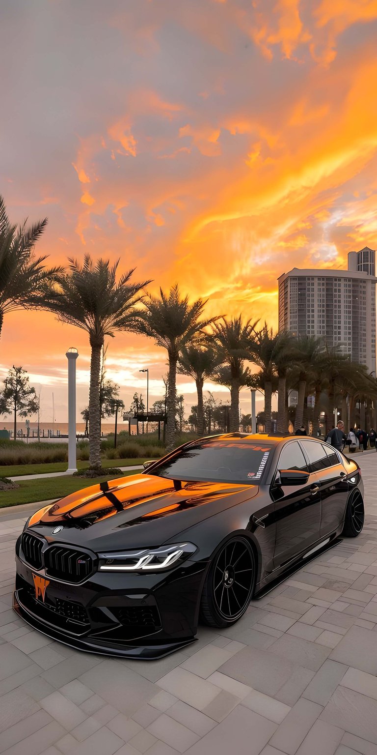 Download this stunning 4K wallpaper of a sleek BMW M5, perfect for your iPhone. The wallpaper showcases the car's low profile, the orange sunset reflection, and the sleek black rims.